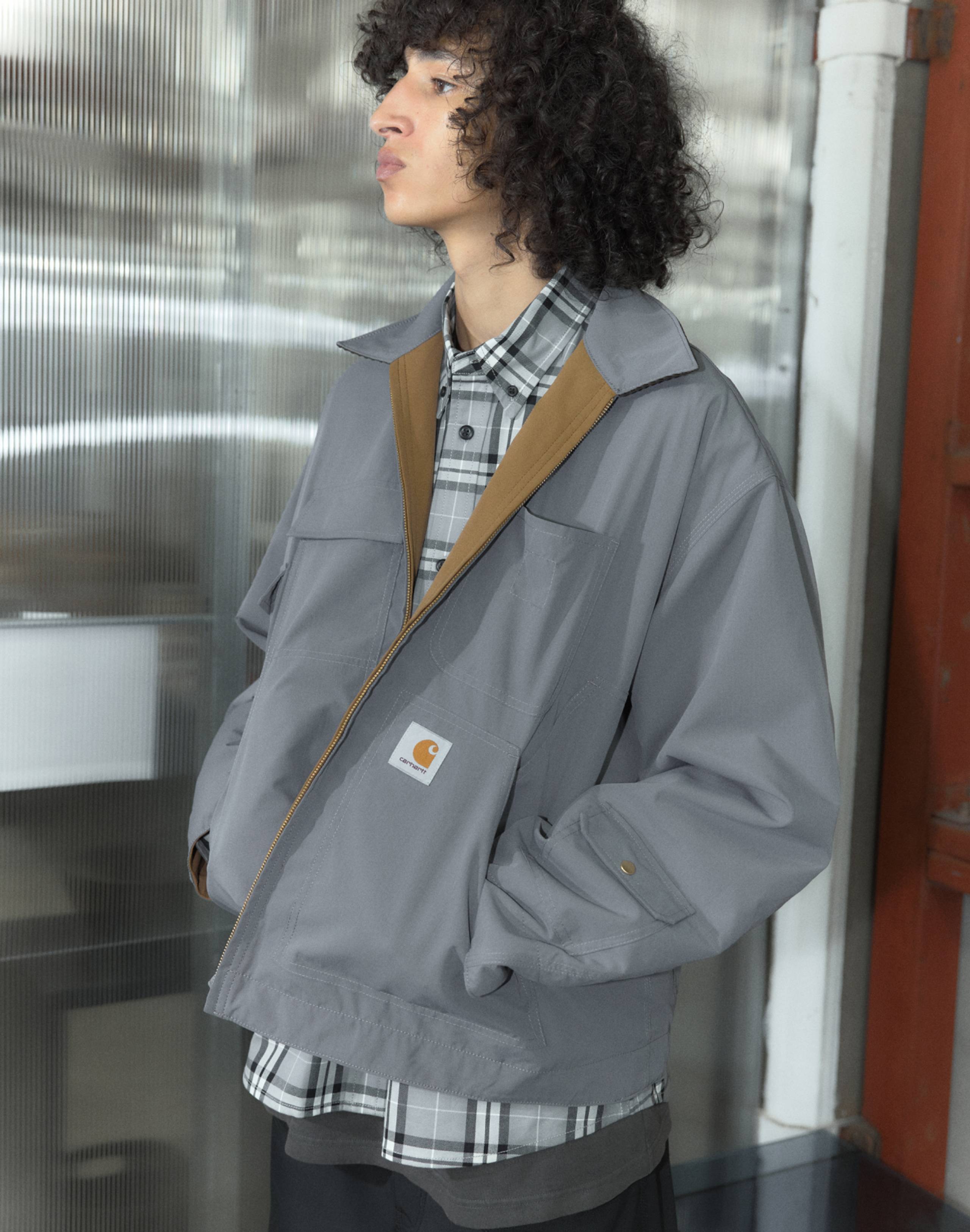 Model wearing Carhartt WIP x INVINCIBLE® Reversible Detroit Jacket Max in gray