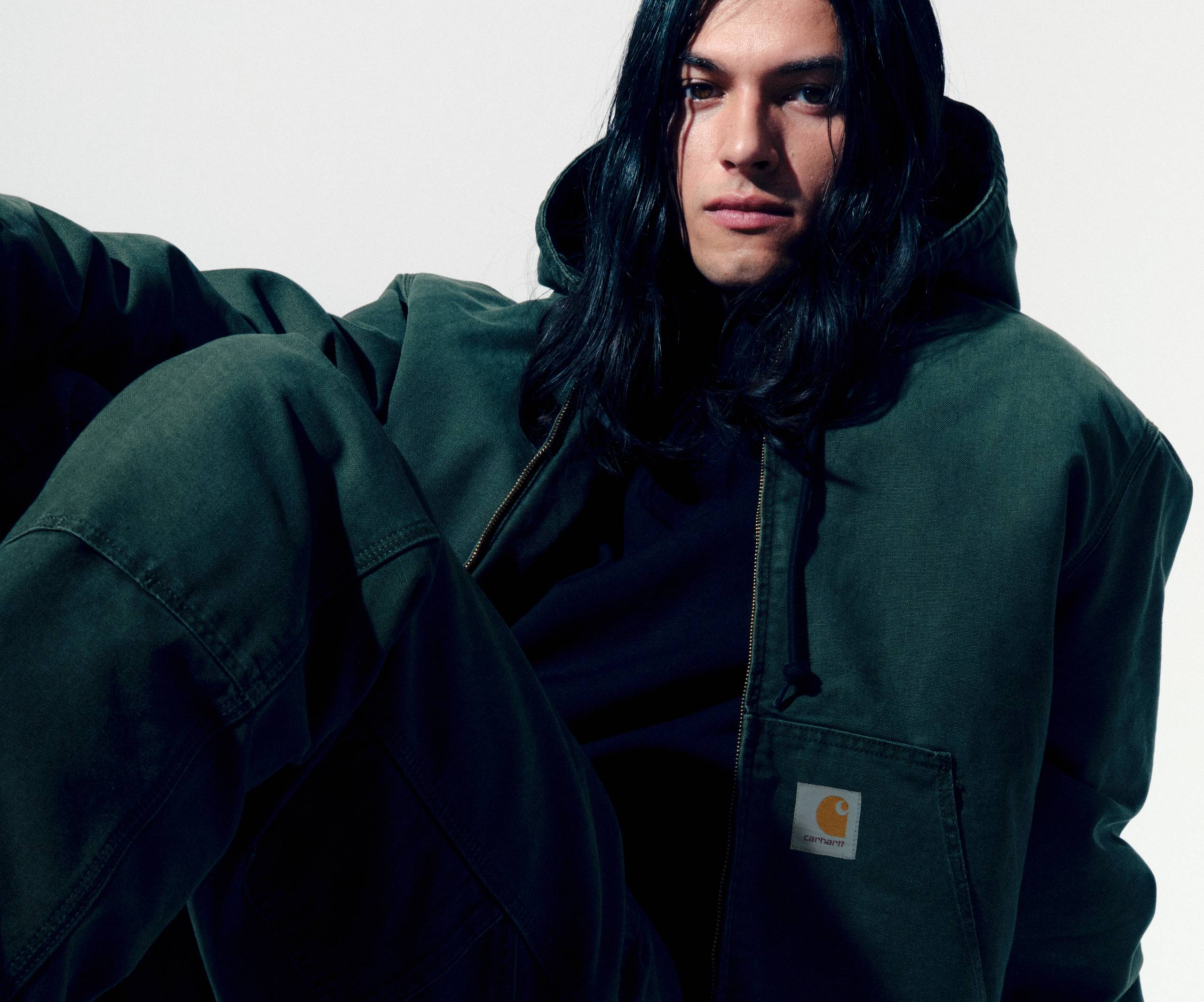 Model sitting on the floor wearing an Active Jacket and Double Knee Pants in Olive
