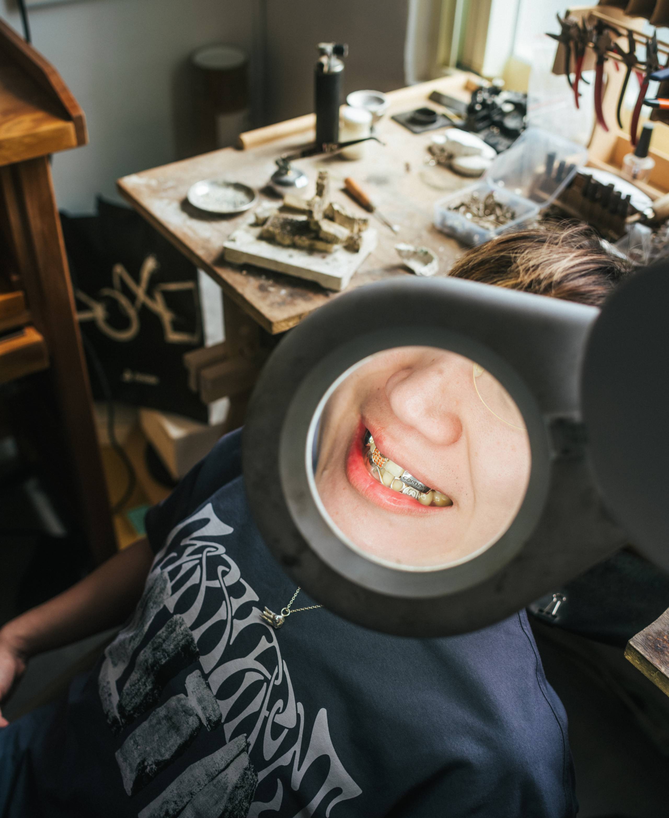 Jewelry Designer Eric Wu working in studio with close up of gold grill jewelry