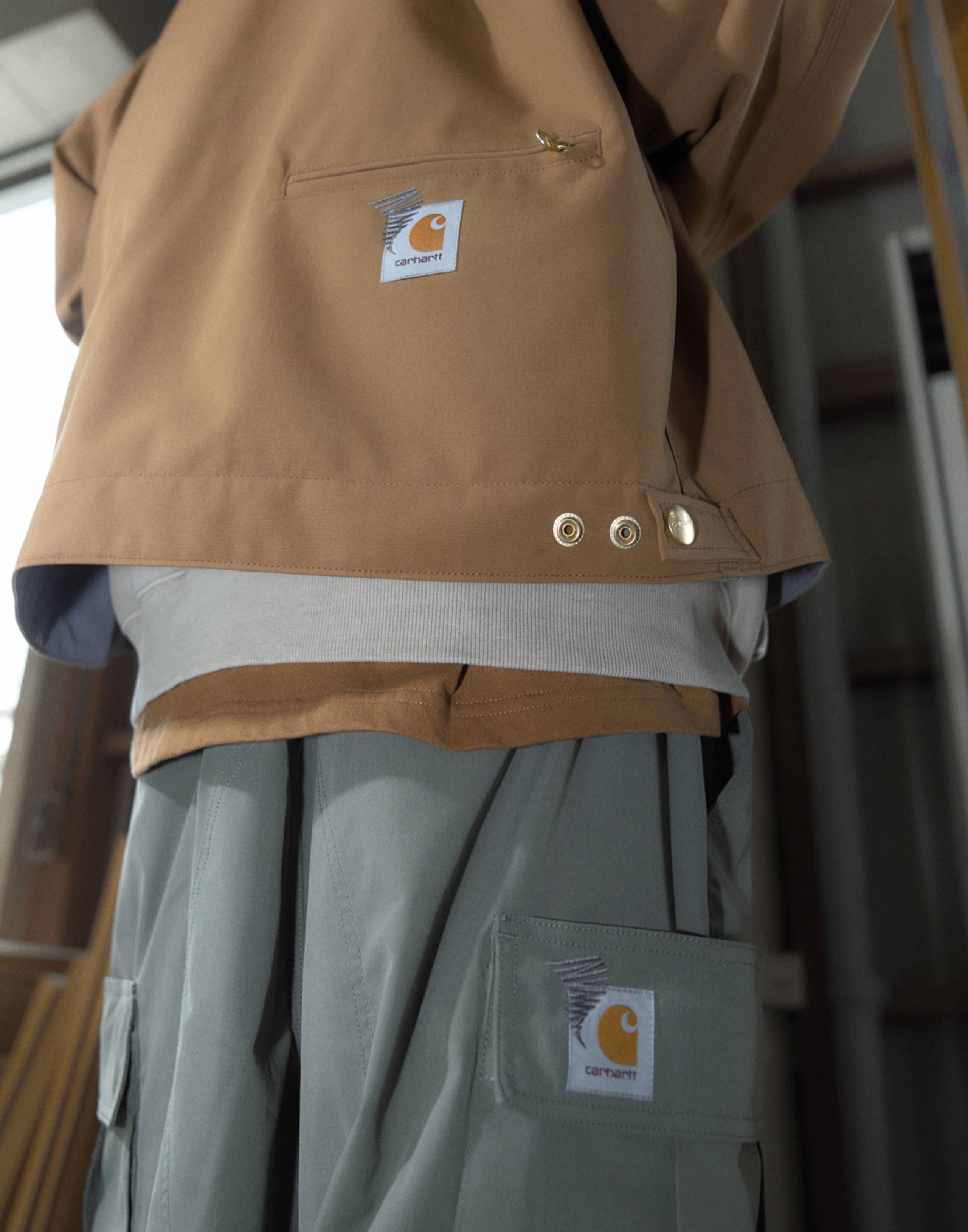 Model wearing Carhartt WIP x INVINCIBLE® Reversible Detroit Jacket Max in Hamilton Brown & Carhartt WIP x INVINCIBLE® cargo pant in gray