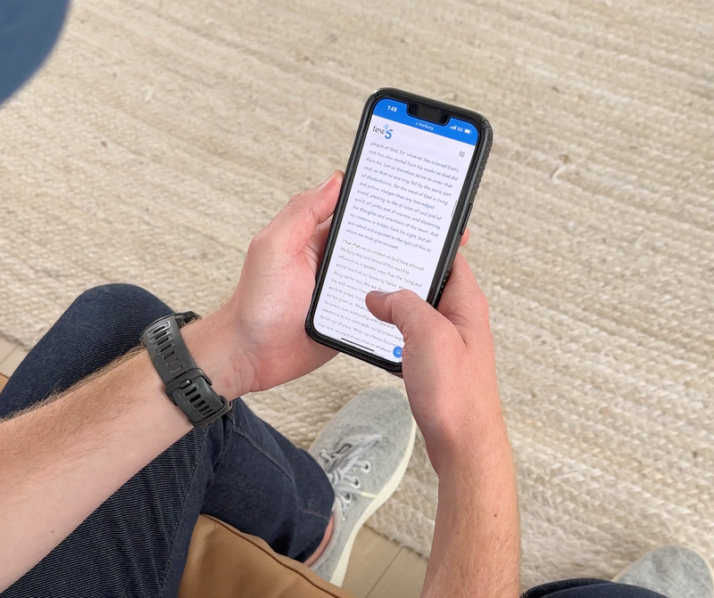 man holding phone reading First15 devotional