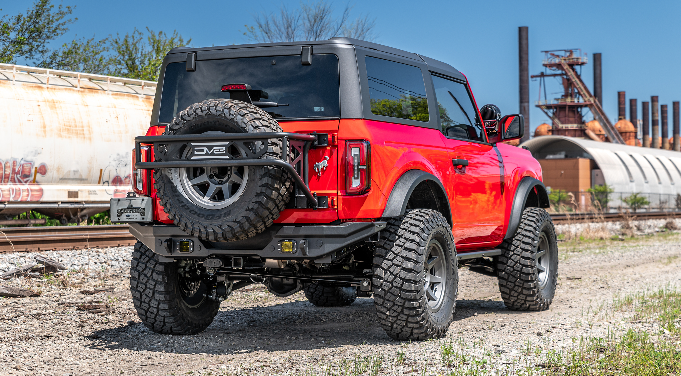Red Jeep near a railway with an mbrp exhaust
