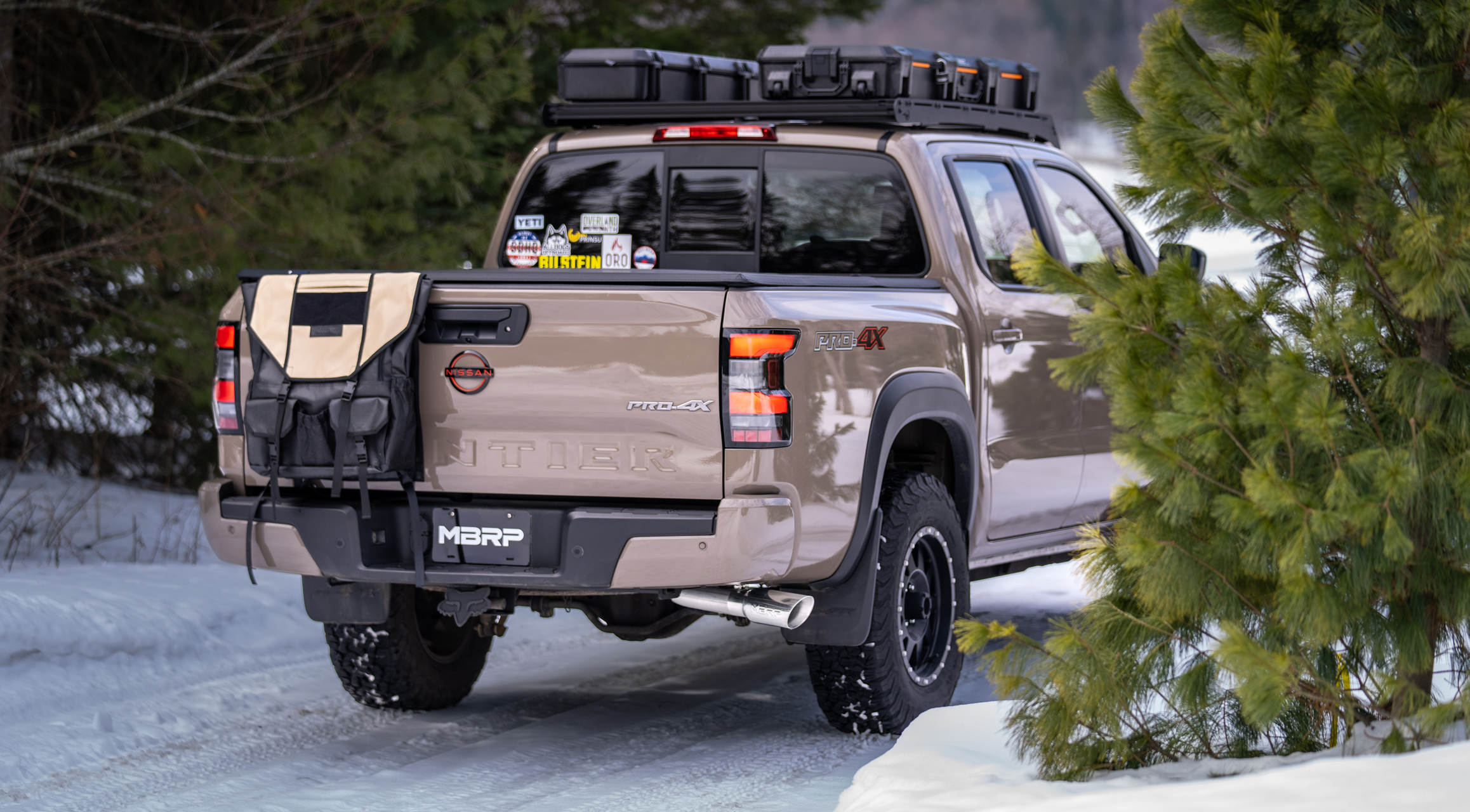 Beige Nissan Frontier with an mbrp exhaust system installed driving around in winter