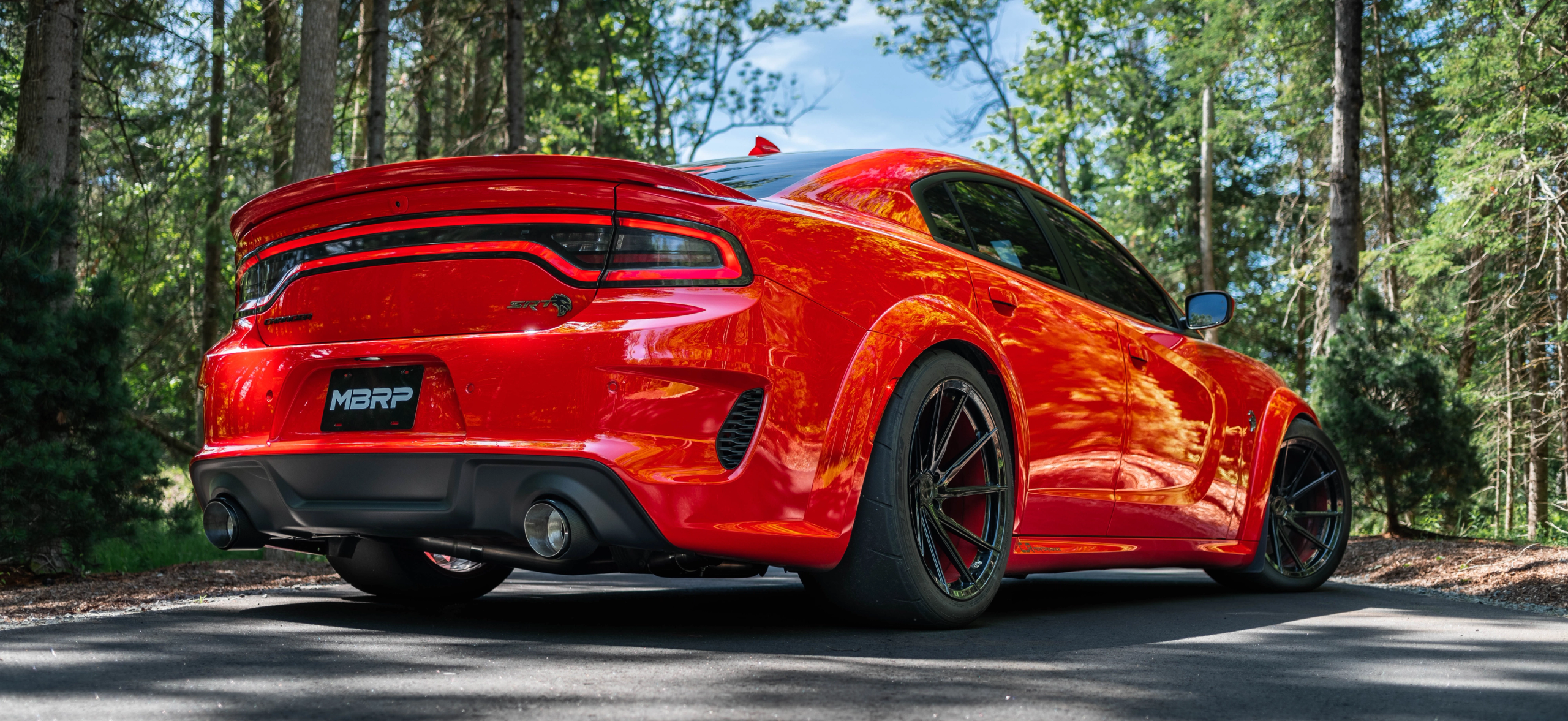 Red Dodge Charger SRT in the summer showing an mbrp exhaust installed