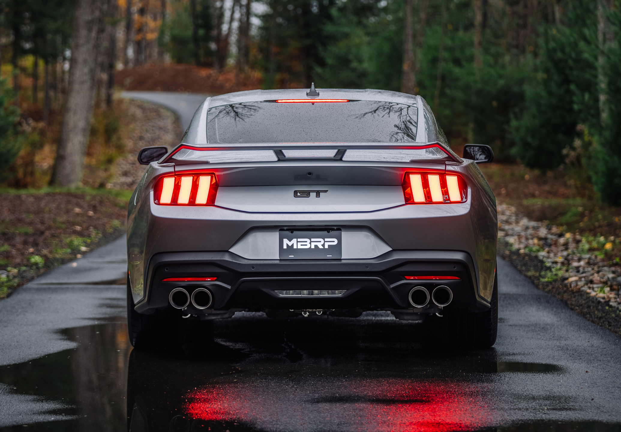 Silver Ford GT Mustang with an mbrp exhaust kit on a roadway in fall after a rainfall