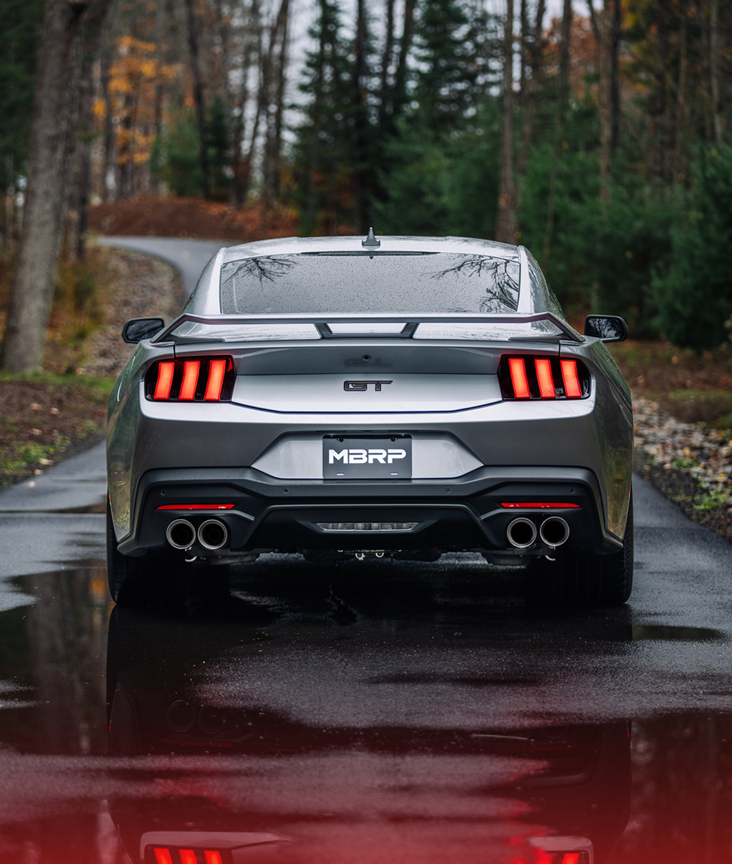 Silver Ford GT Mustang with an mbrp exhaust kit on a roadway in fall after a rainfall