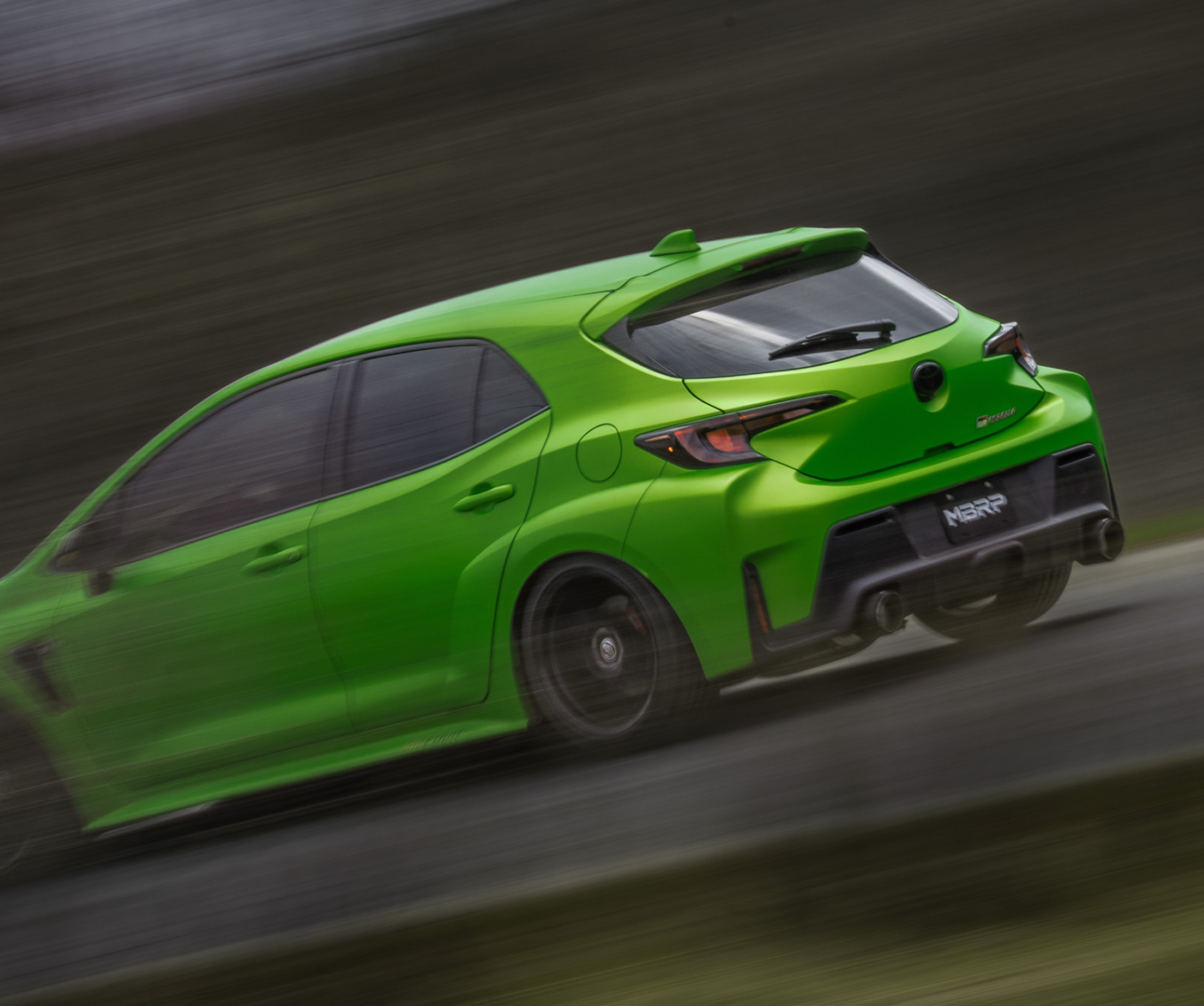 Green Toyota Corolla driving fast