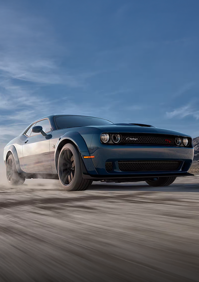 Dodge Challenger driving fast with blue skies