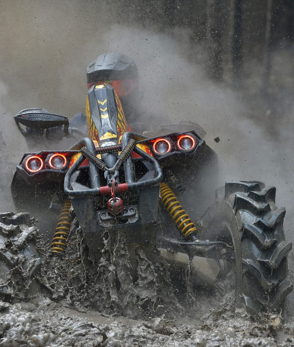 ATV with an mbrp exhaust driving through mud