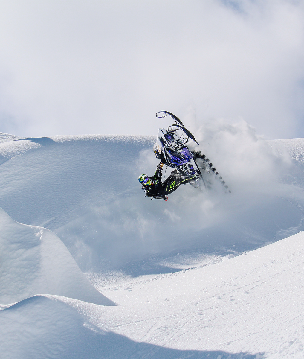 Snowmobile with mbrp exhaust in the mountains doing a trick