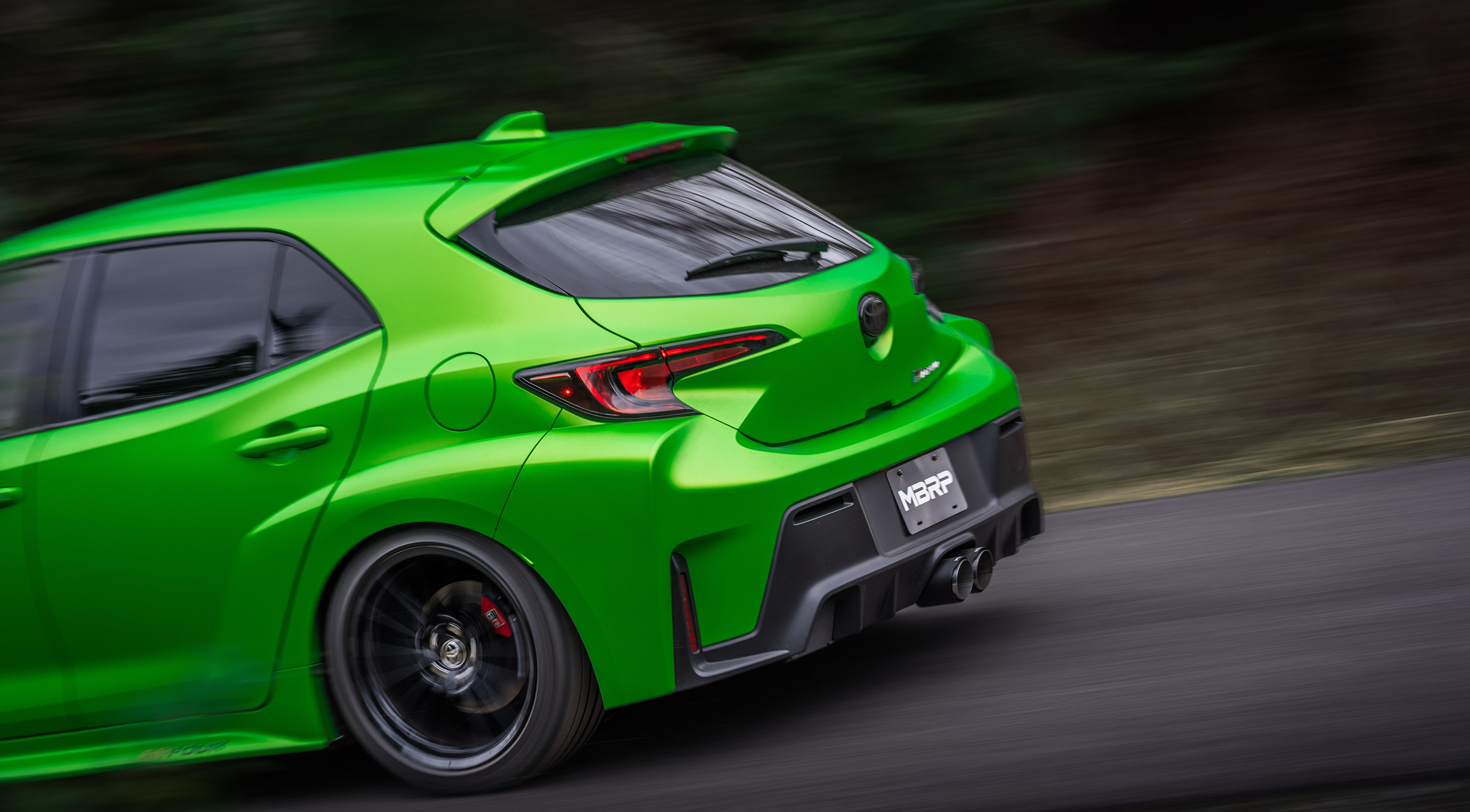Green Toyota Carolla moving fast while showing off an mbrp exhaust