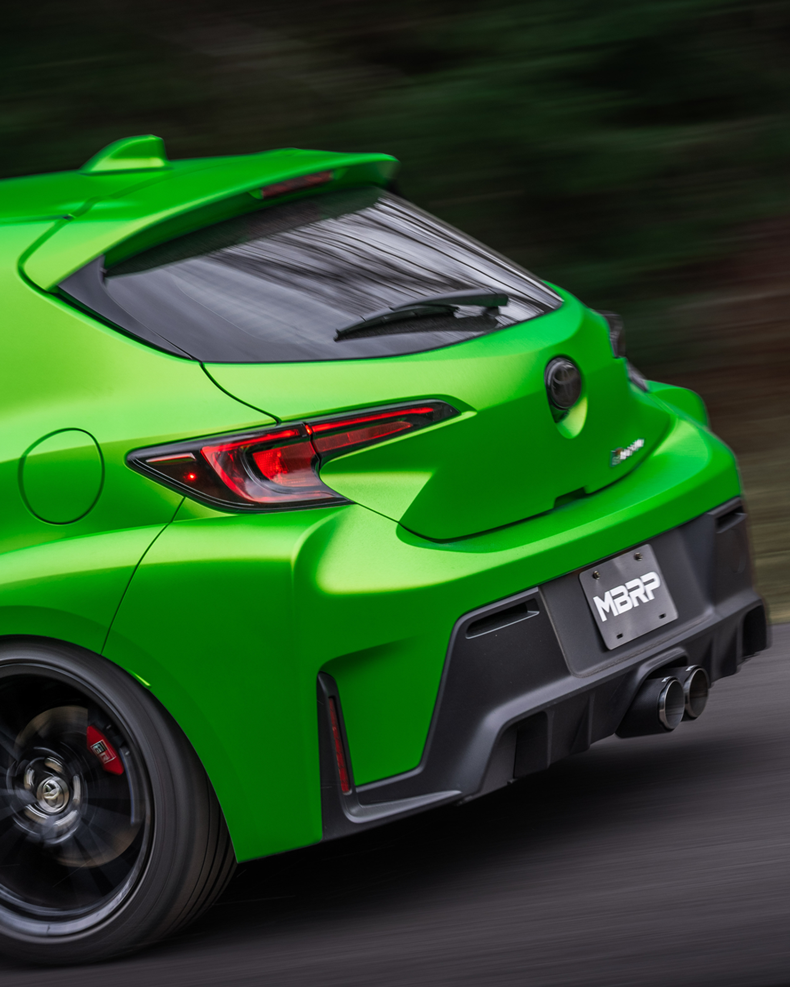 Green Toyota Carolla moving fast while showing off an mbrp exhaust