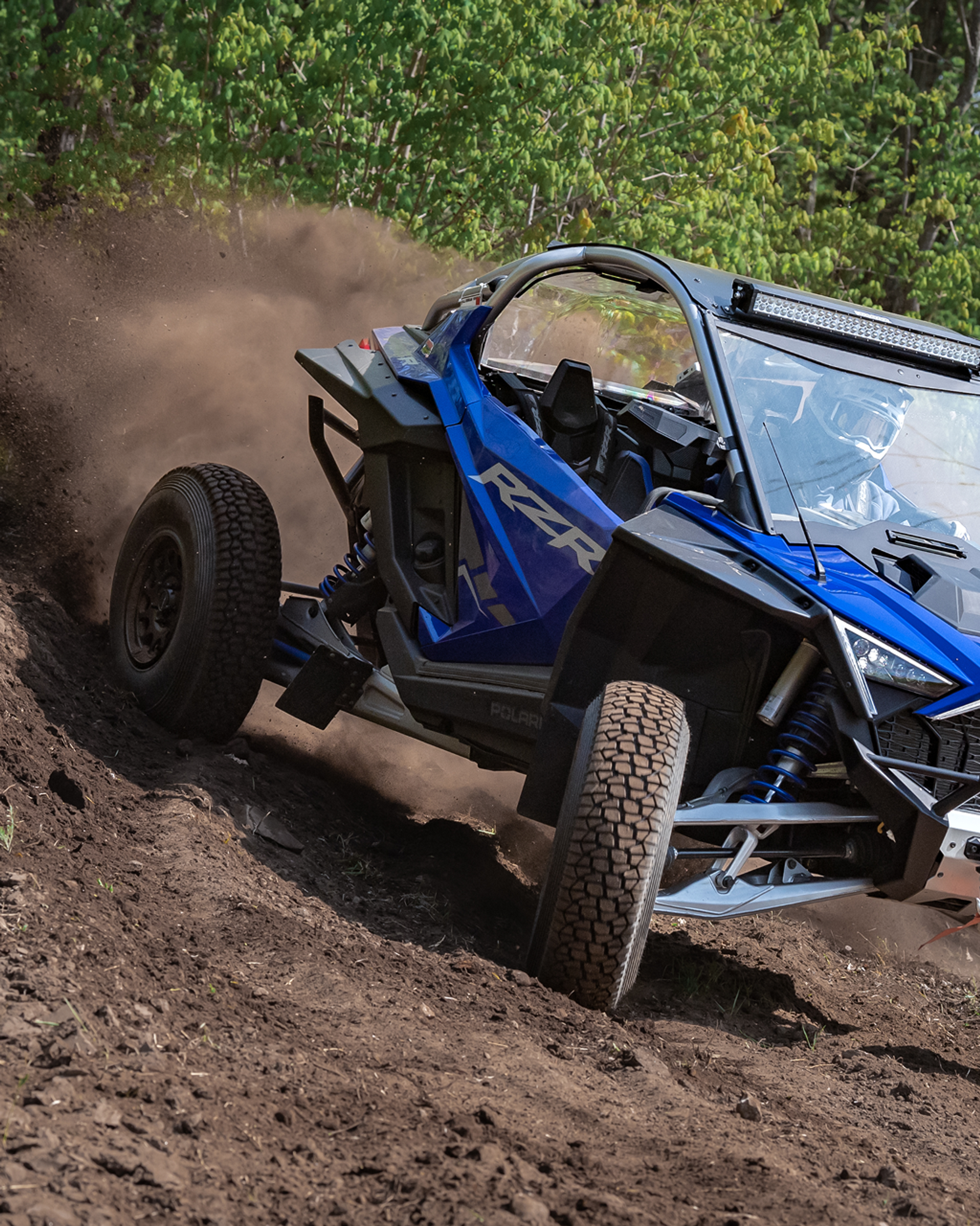 RXR SXS driving through the woods throwing up dirt after