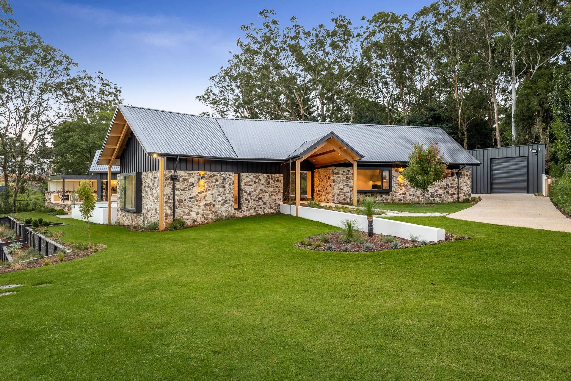 Glencoe Court, a stone and dark steel home with timber gables on a wide lawn, built by Mark Winter Constructions