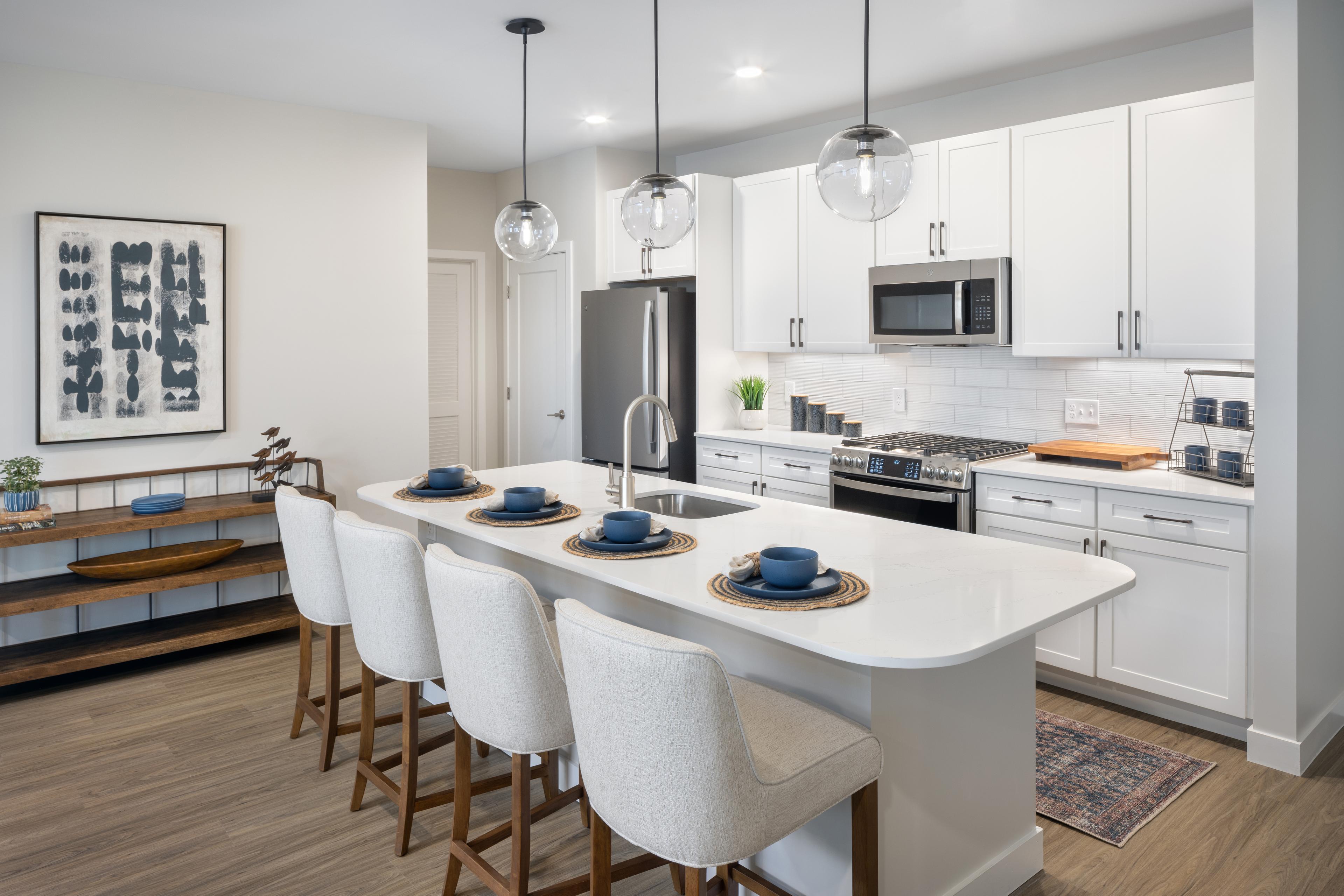 Kitchen with island, barstools, hanging lights over the island