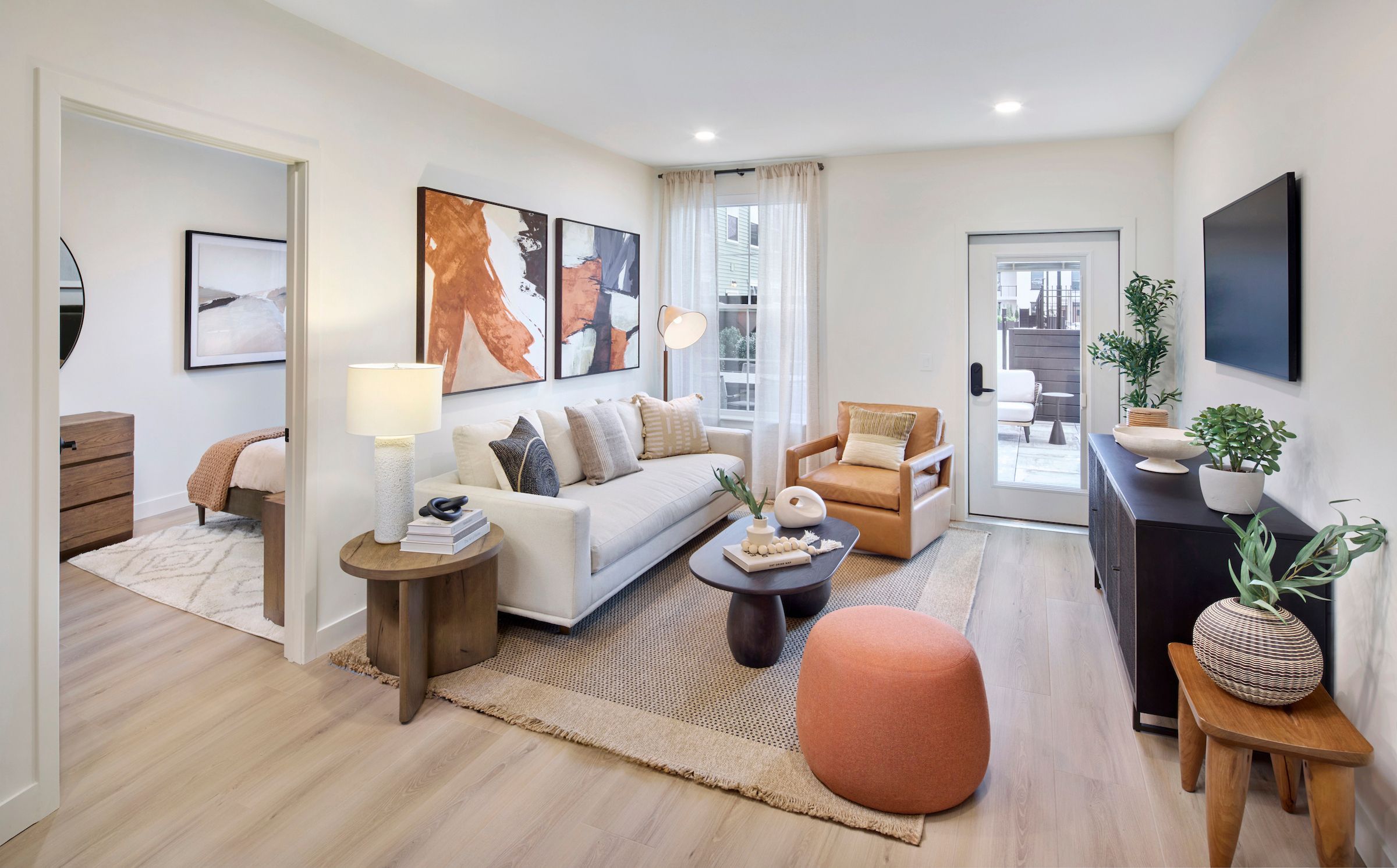 Modern open-concept kitchen and living room with wood floors, island seating, and large windows.