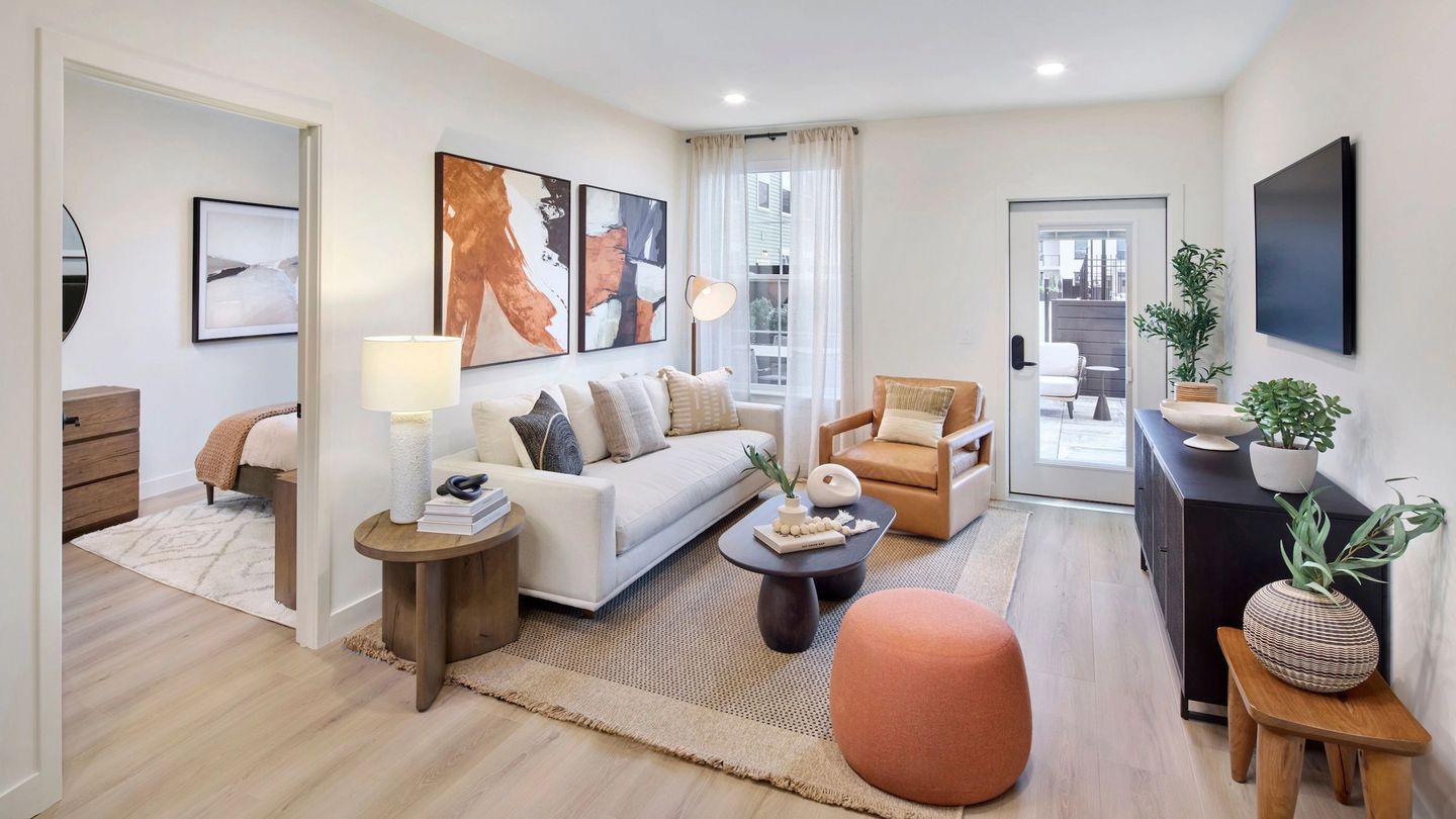 Modern open-concept kitchen and living room with wood floors, island seating, and large windows.