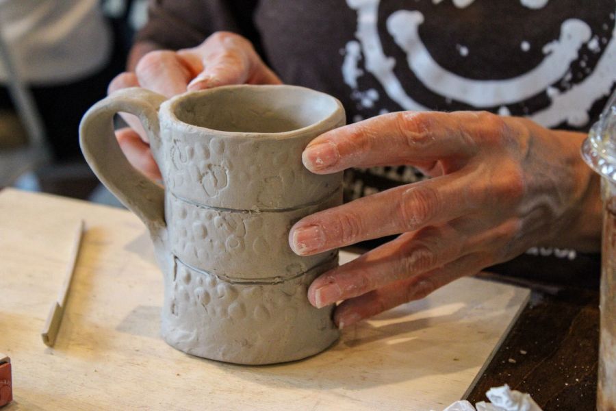 Hands touching and smoothing the rim of a handmade mug. 