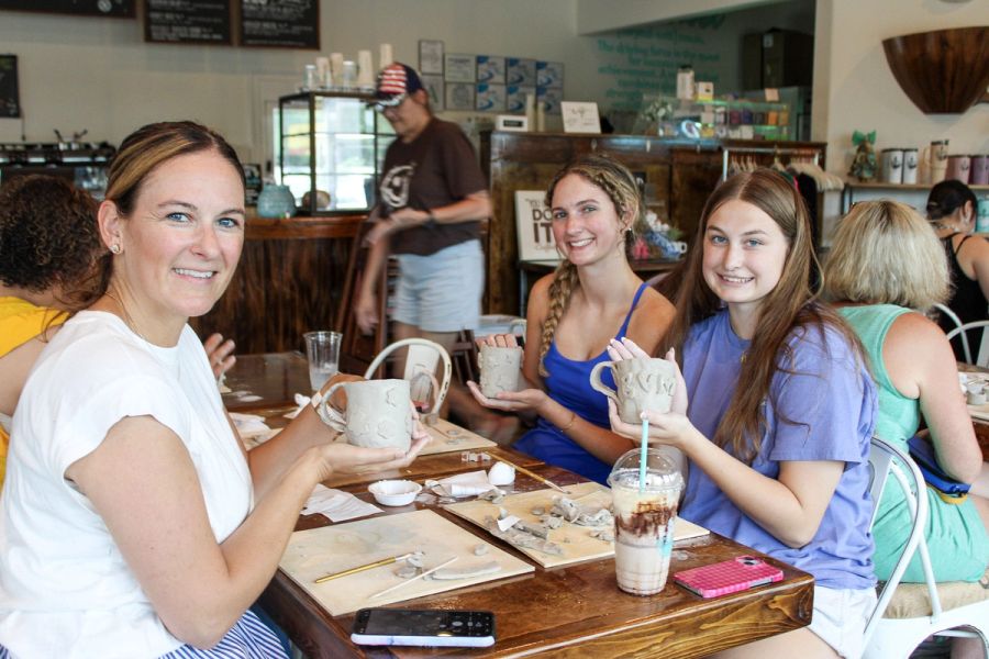 A family of women displaying their hand made mugs at a pottery workshop