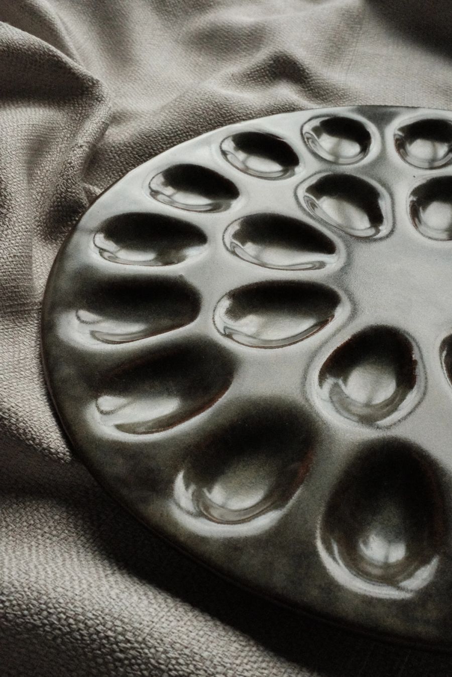 A close, angled view of a dark green deviled-egg tray showing the hand-formed egg wells