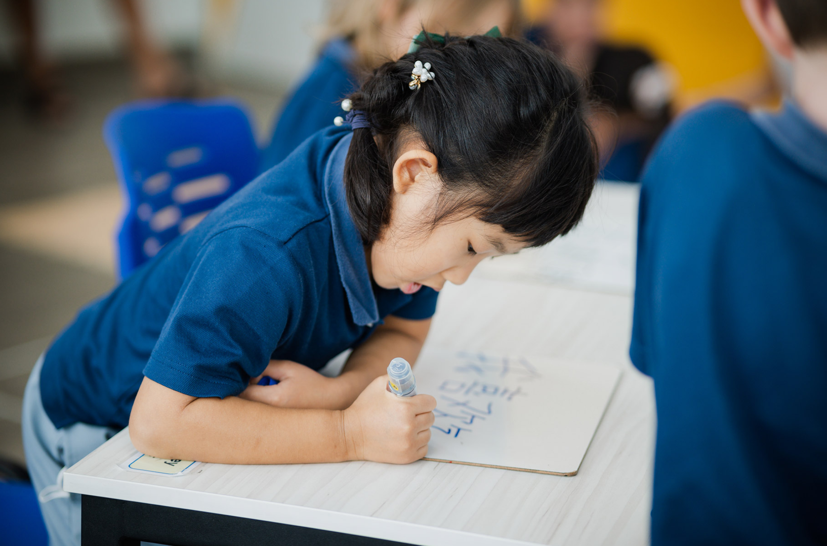 Young student writing Mandarin characters in class