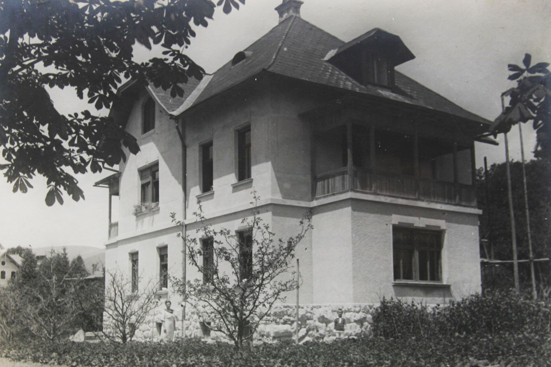 Historic photo of the facade of Villa Josephine, highlighting the original architecture of the village in Bled, with trees around and a sunny climate.