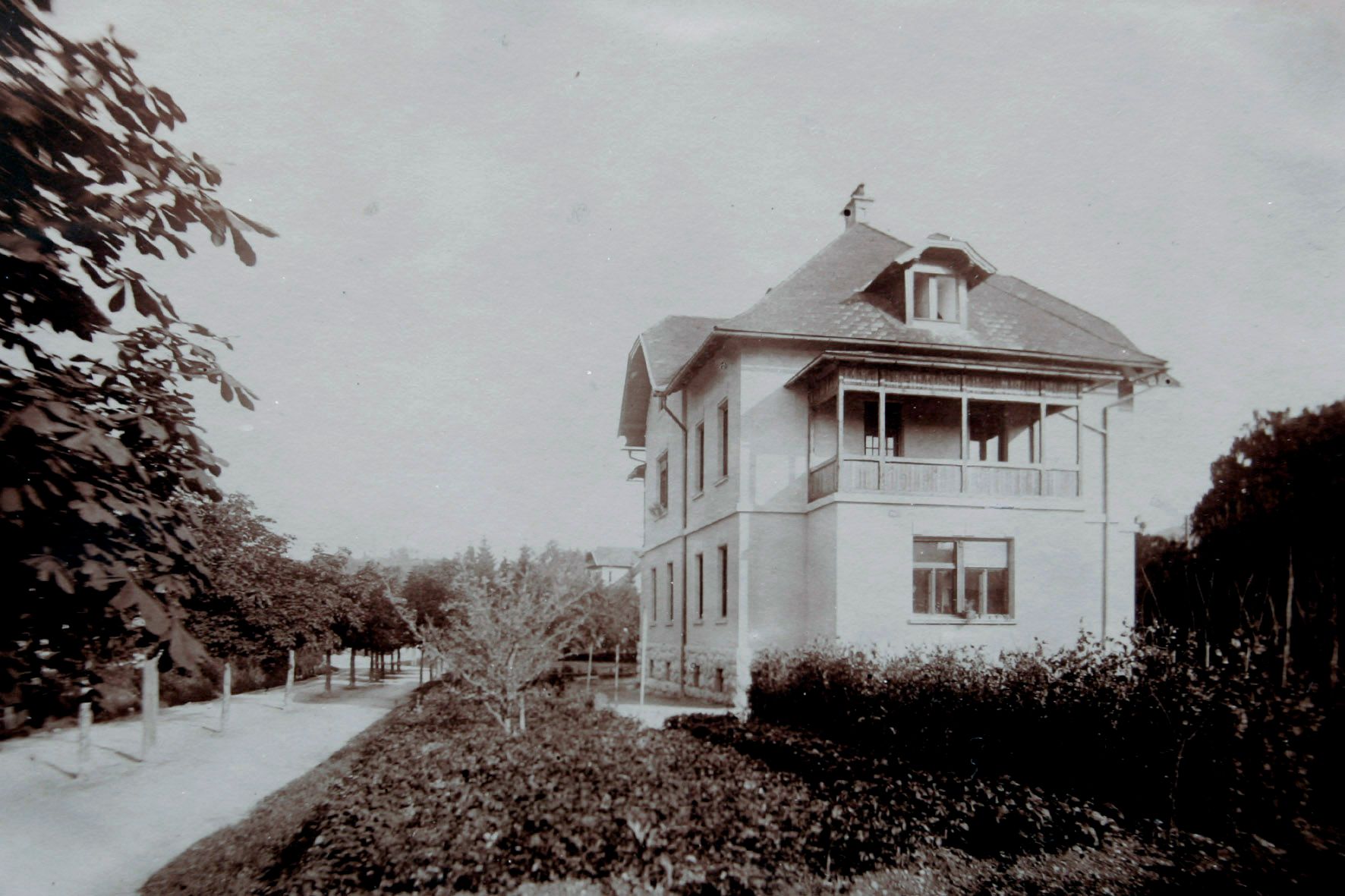 Historic black and white photo of Josephine Village in Bled during winter, with snow covering the street and trees, highlighting the village's classical architecture.