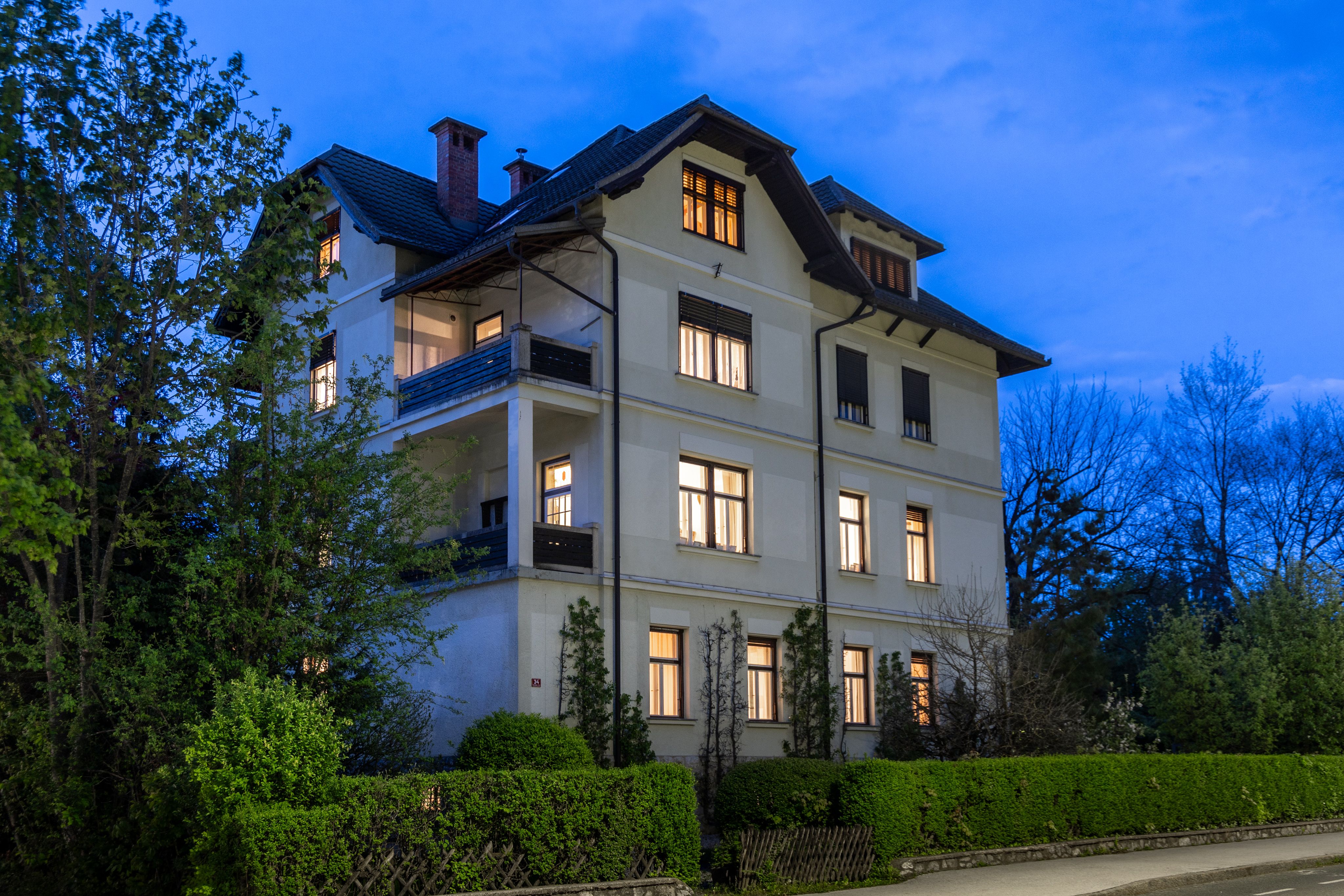Villa Josephine at night, softly lit, surrounded by gardens and trees, offering a charming view with the lighting from the windows.