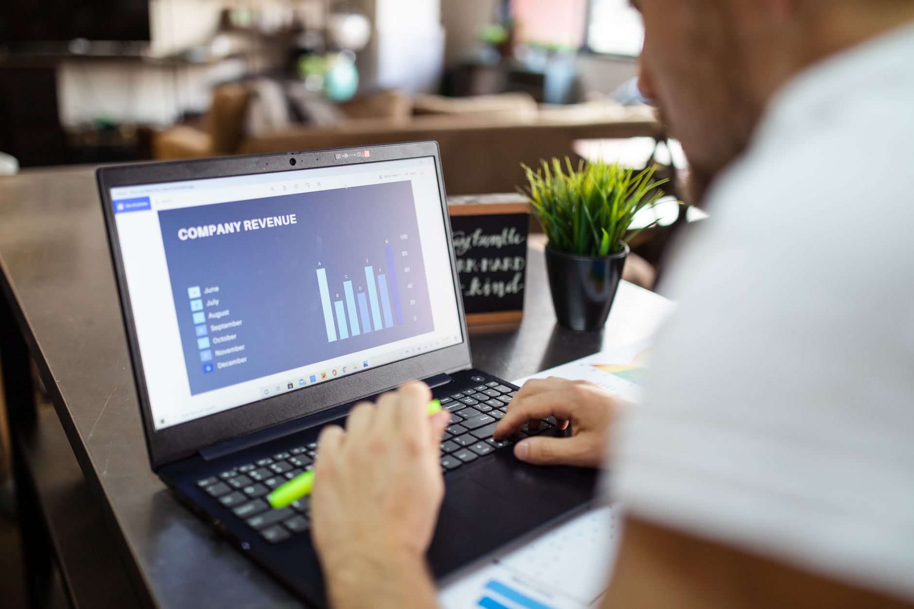 Person reviewing a company revenue chart on a laptop in a cafe