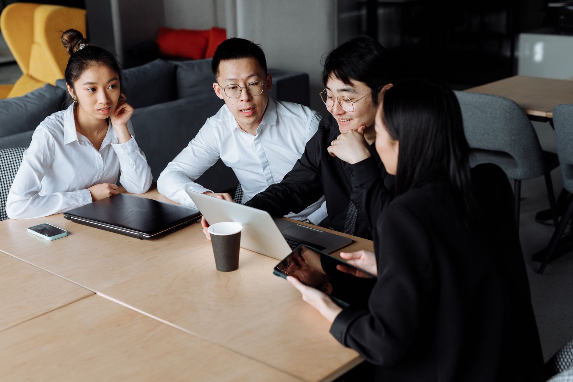 Four colleagues gathered around laptops in a dim modern office