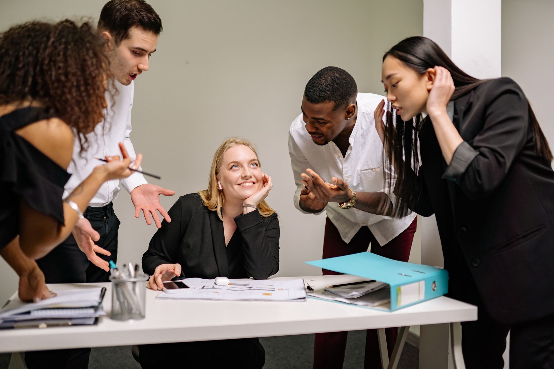Colleagues crowding around a smiling coworker at a desk