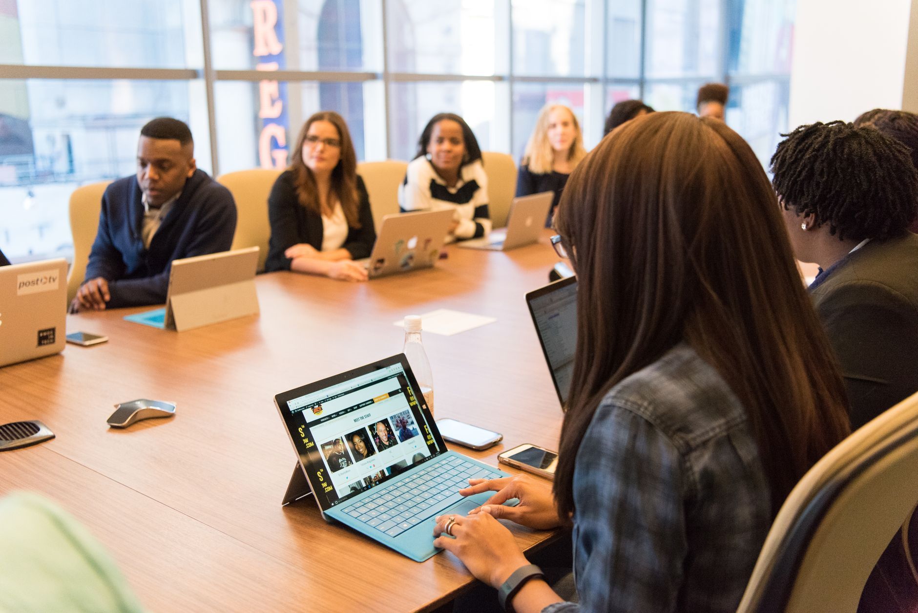 Team seated around a long conference table with laptops open