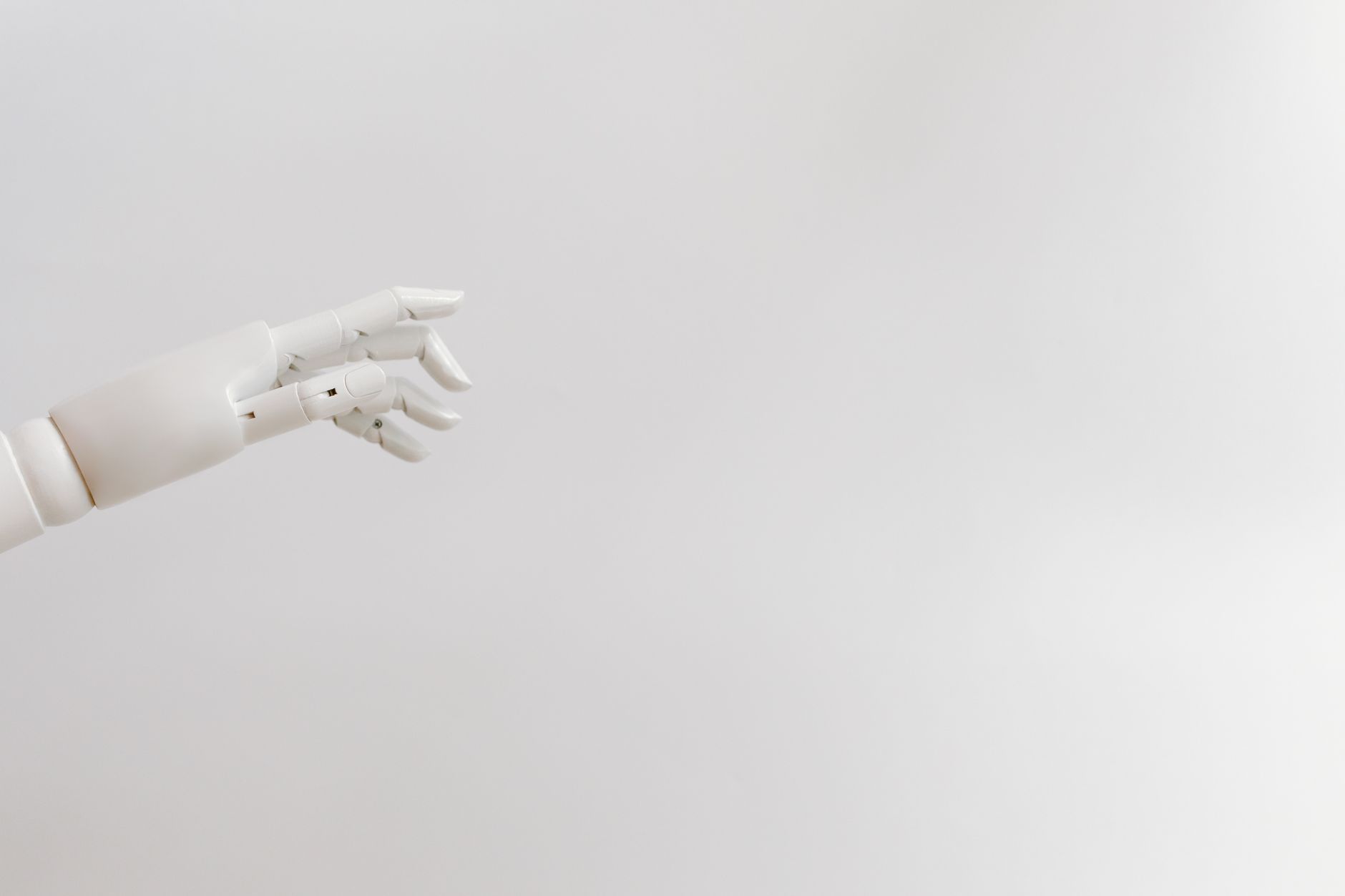 White robotic hand reaching in from the edge of a plain background