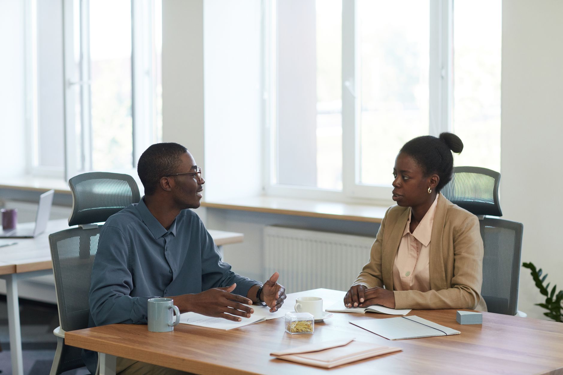 Two professionals having a focused conversation across a meeting table