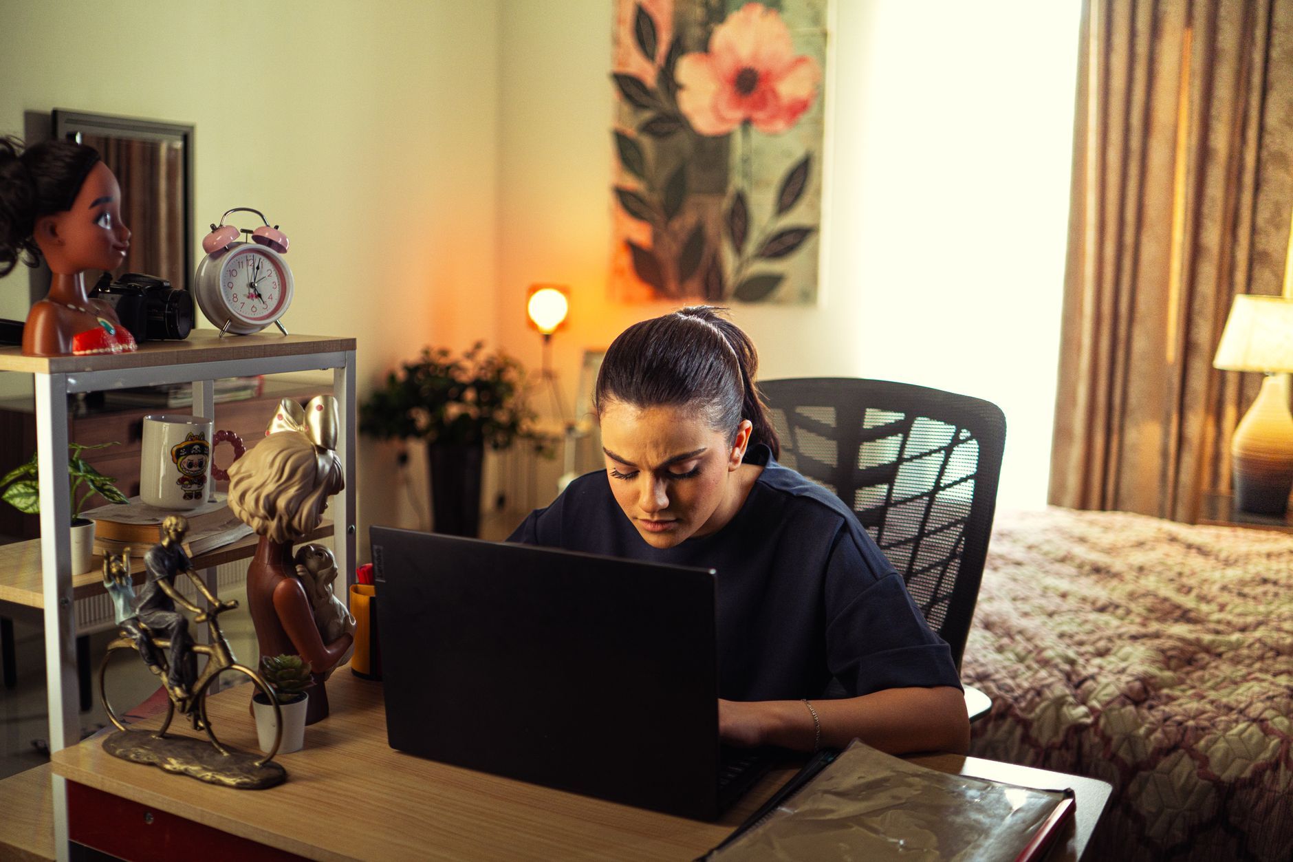 Woman with headphones working late on a laptop in a warmly lit bedroom