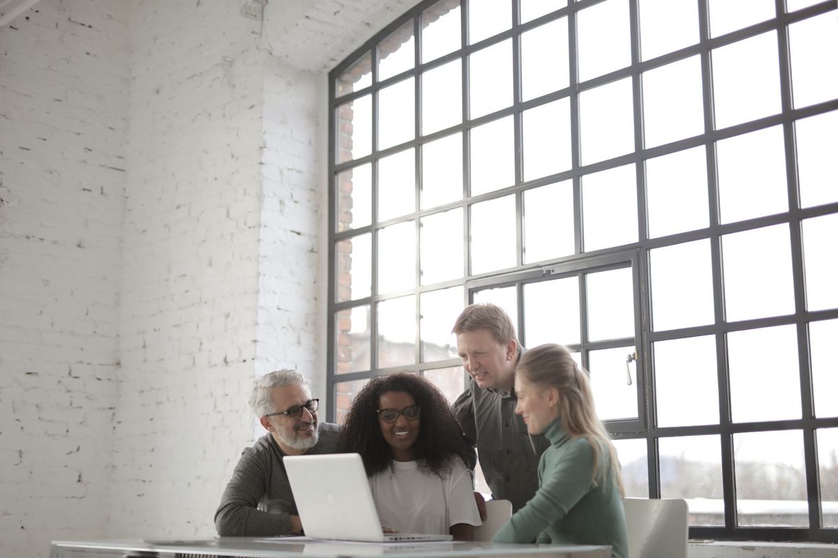 Small group gathered around a laptop in a bright loft office