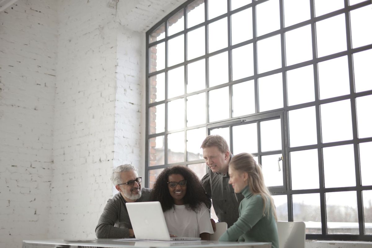 Small group gathered around a laptop in a bright loft office