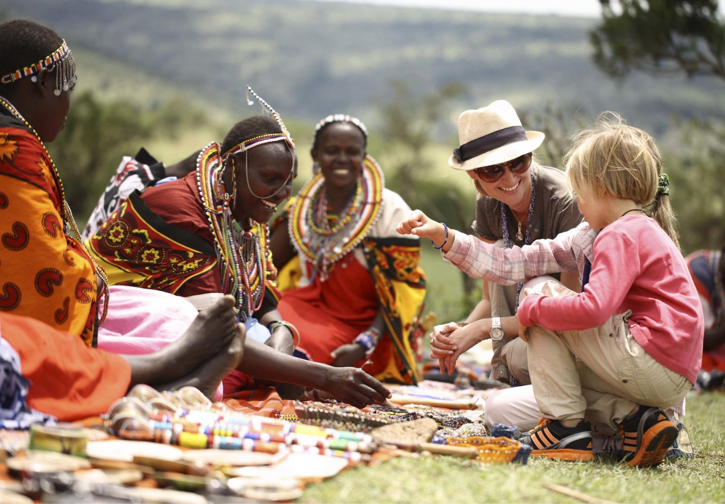 Tourists interacting with Maasai women displaying traditional crafts in Masai Mara, Kenya
