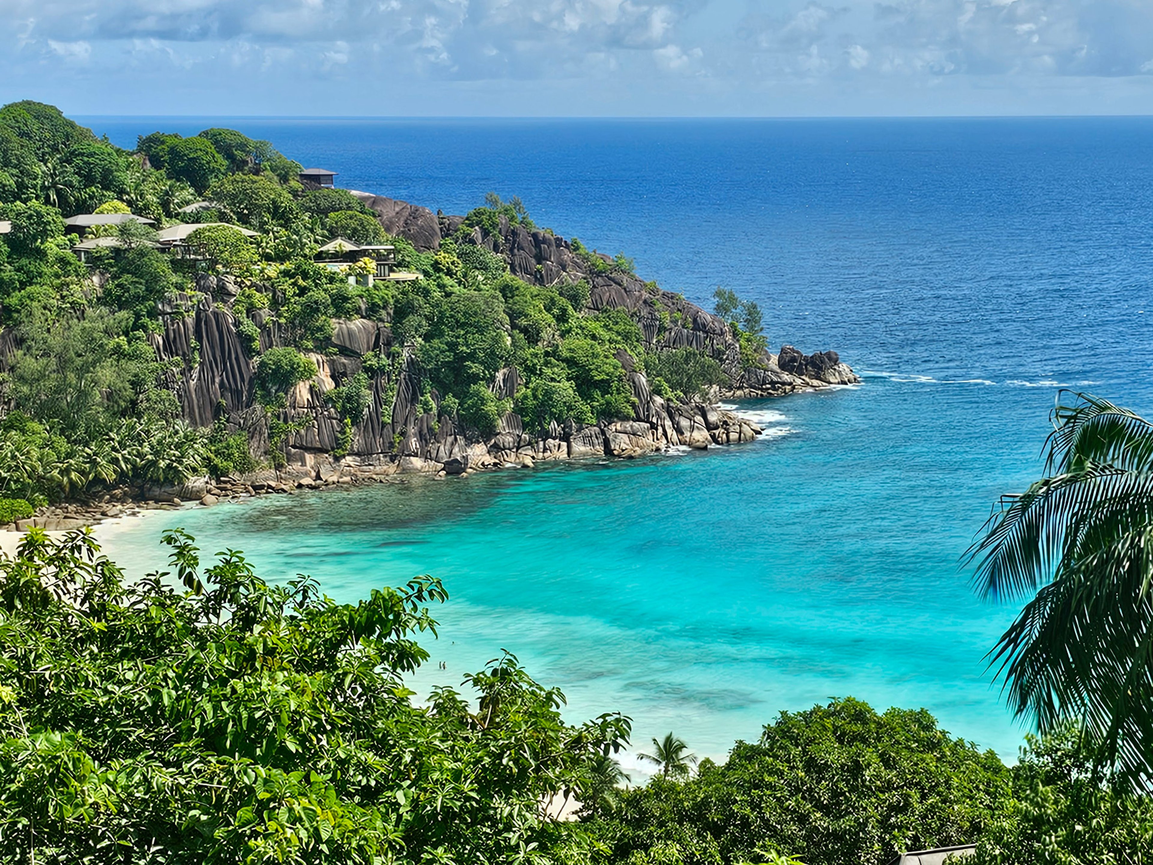 Coastal view of turquoise waters, rocks, and lush greenery