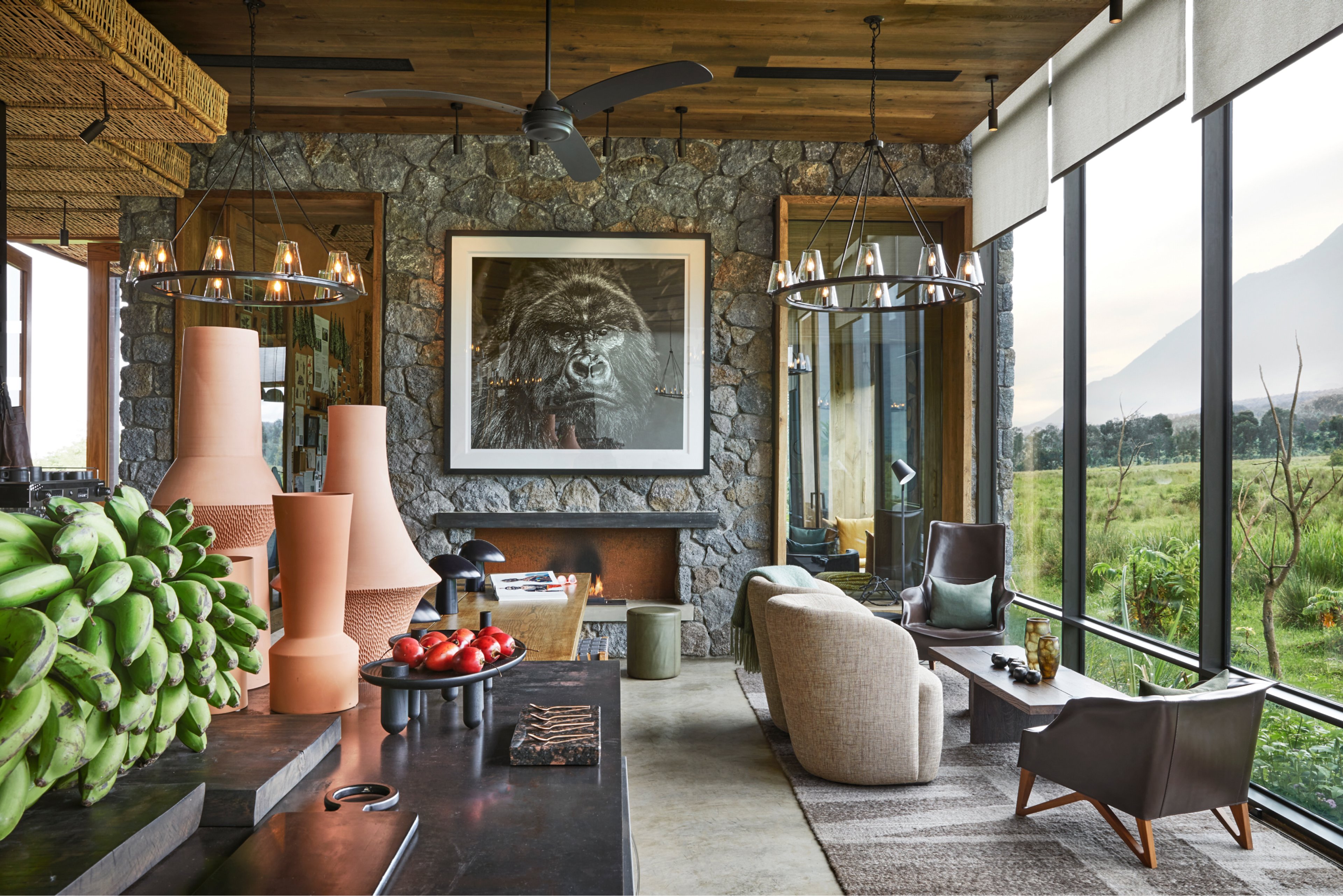 Interior of a luxury lodge with stone walls, modern decor, and large windows overlooking a lush landscape