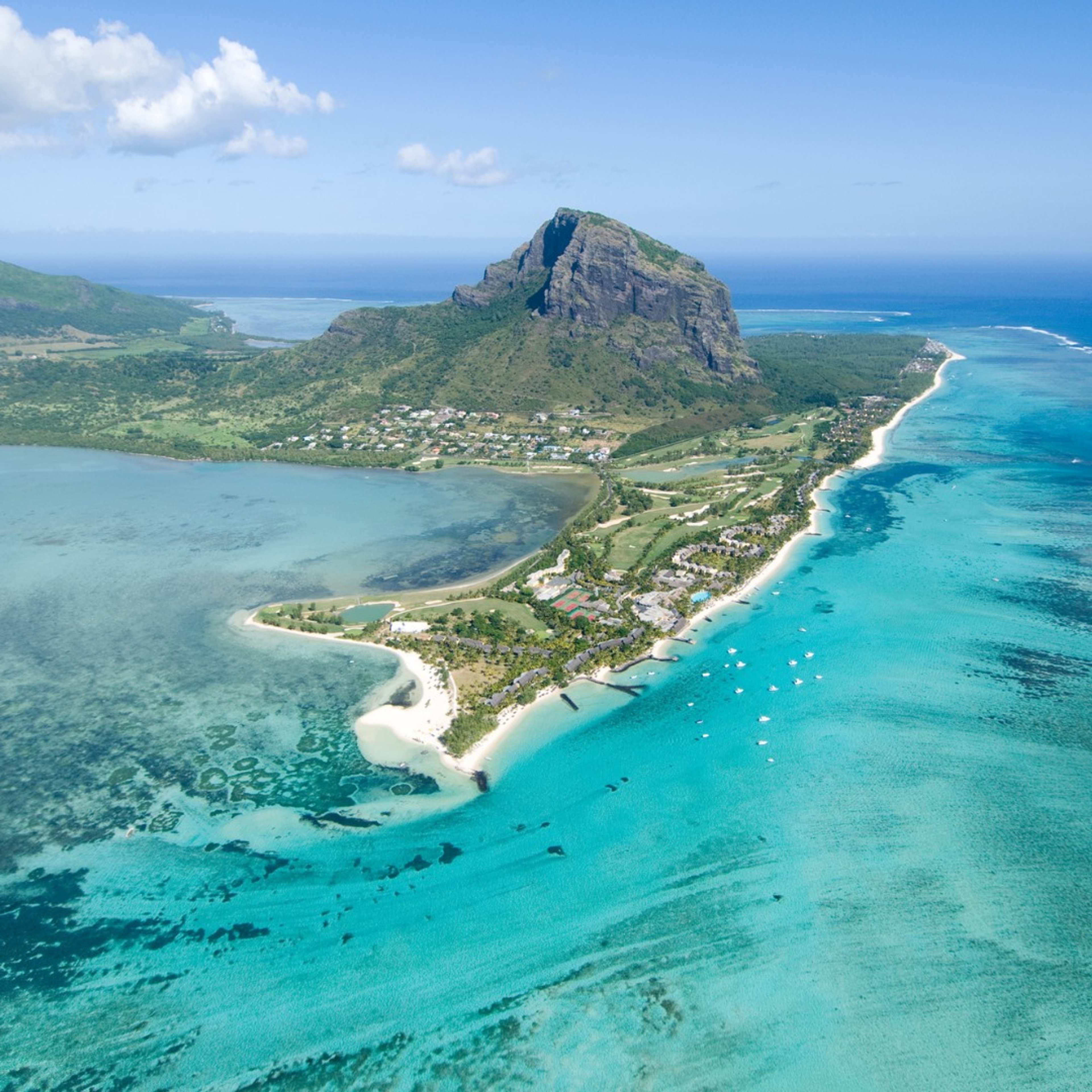 Aerial view of a coastal landscape with turquoise waters and a prominent mountain