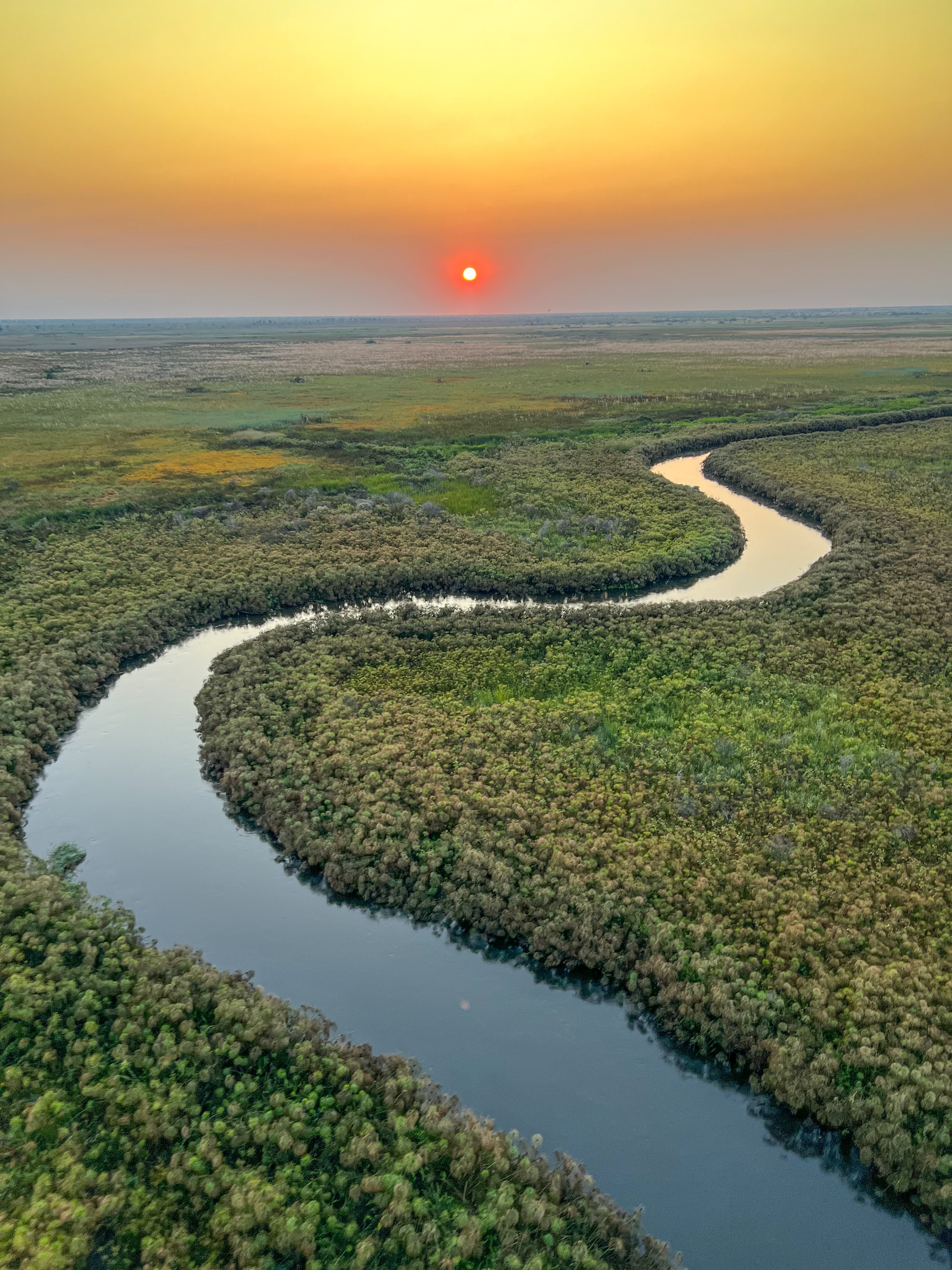 Winding river through a grassy landscape at sunset