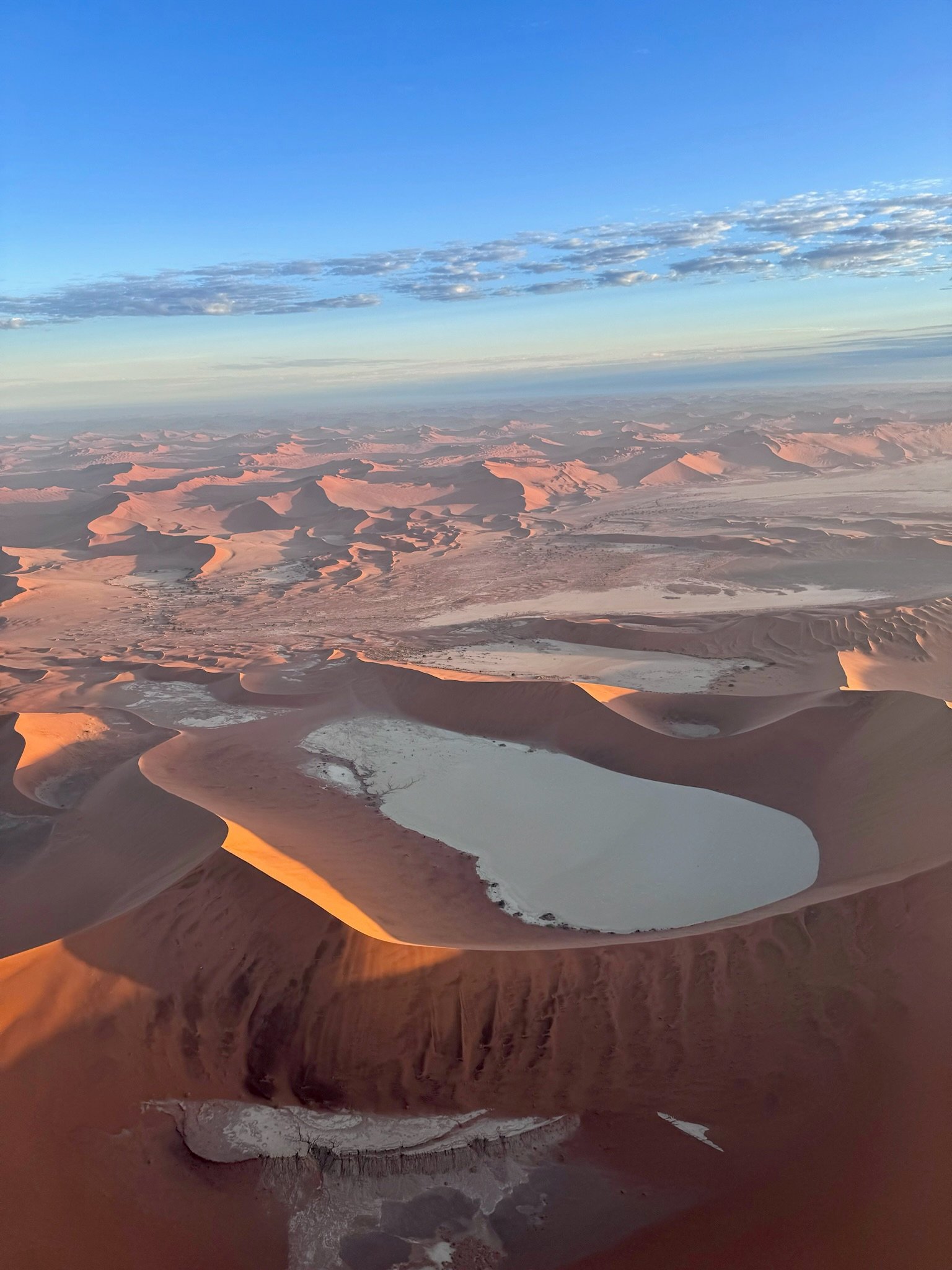 Aerial view of sand dunes and salt pans in Sossusvlei, Namibia, under a clear sky