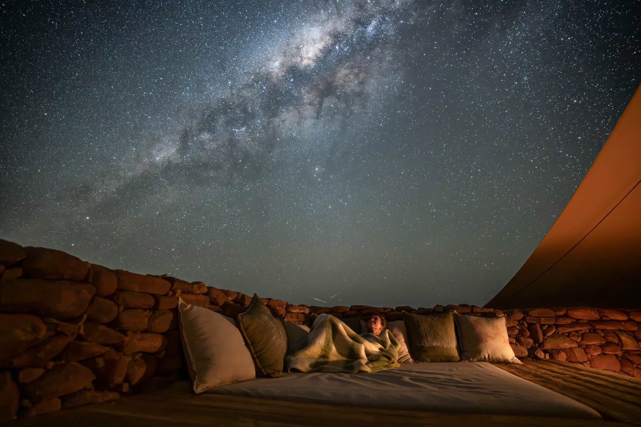 Person lying on an outdoor bed under a starry sky with the Milky Way visible