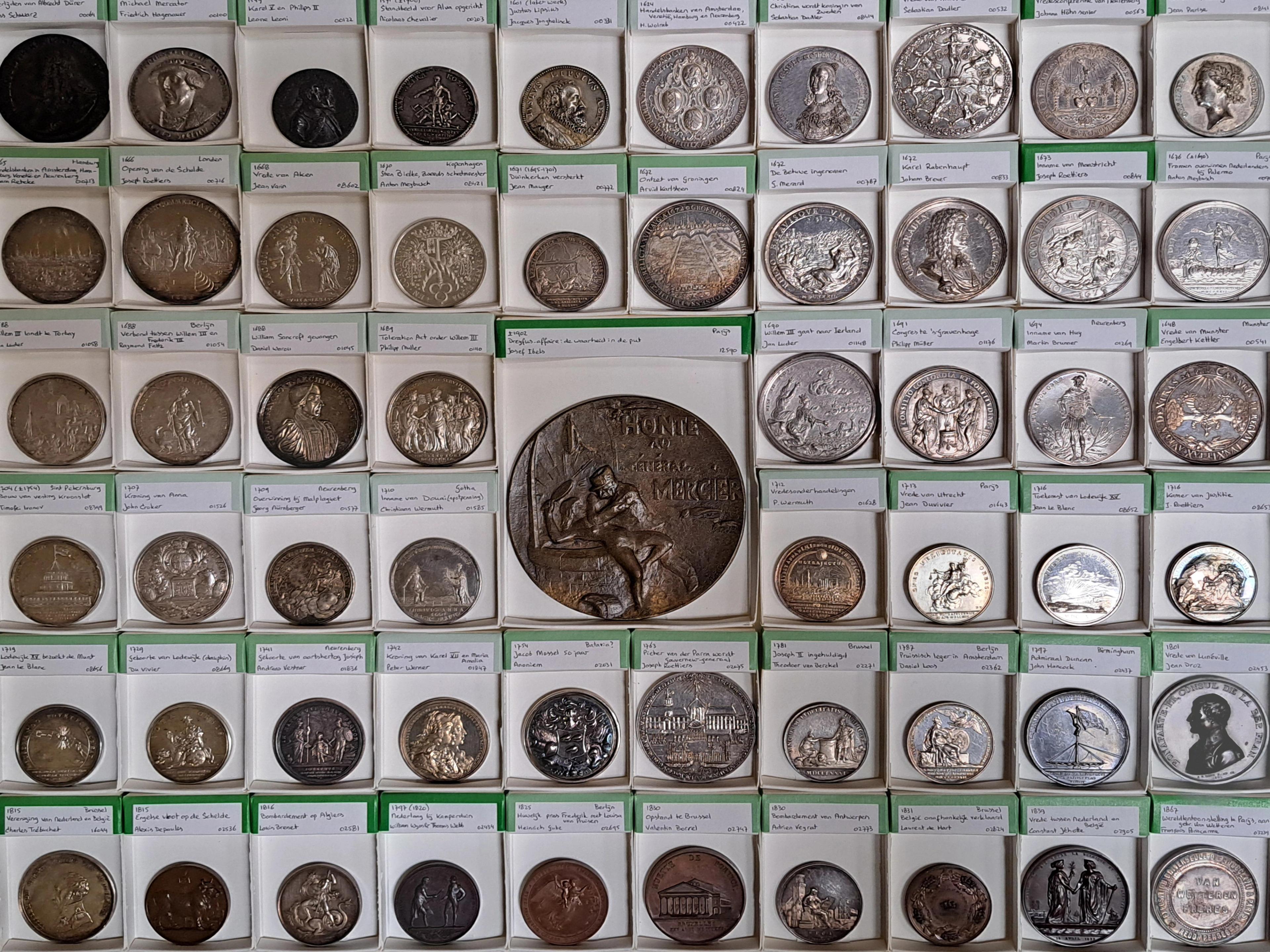 Tentoongestelde penningen en munten in penningbakjes 