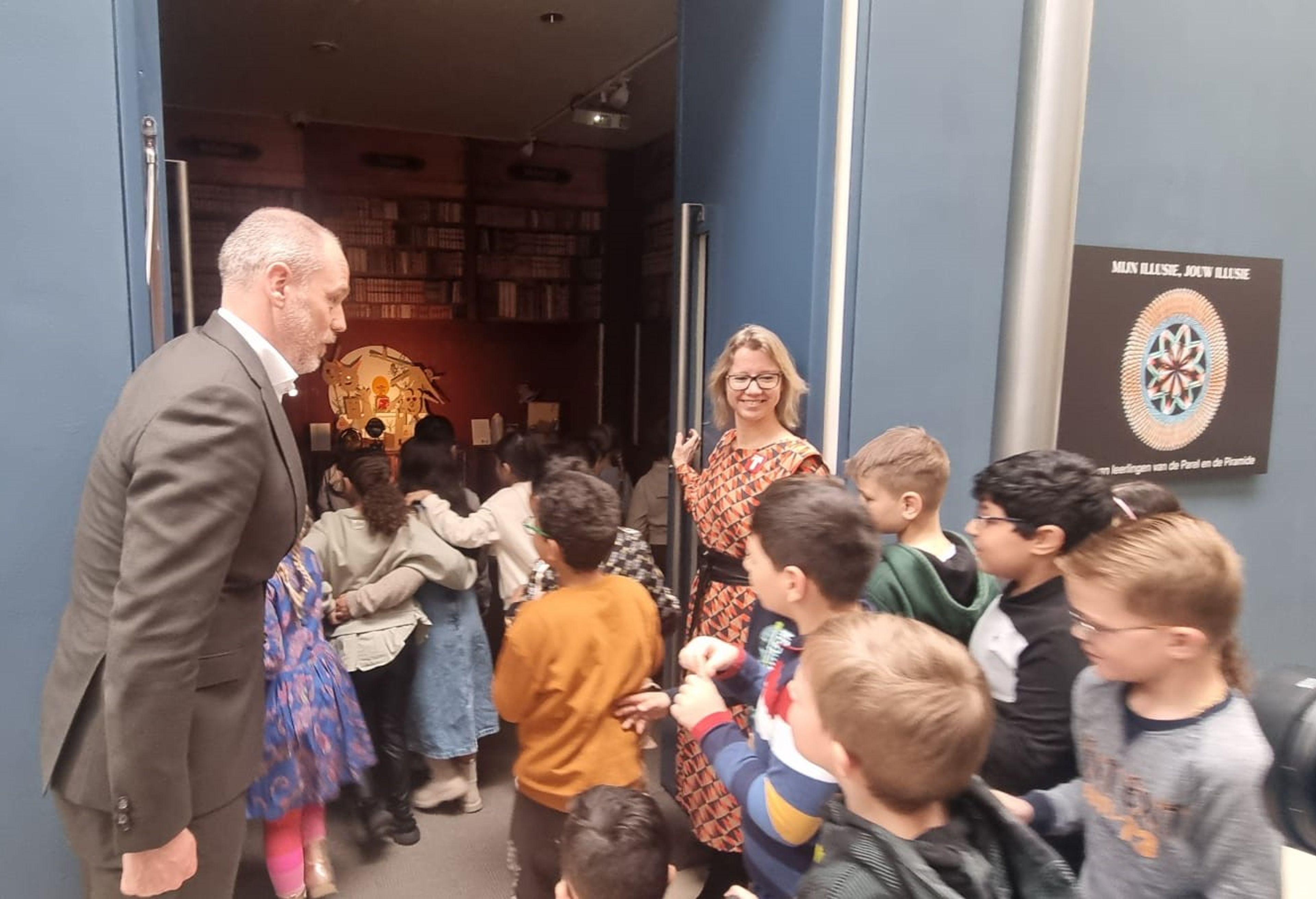 Wethouder Bas van Leeuwen opent de deur van het Boekenkabinet voor de leerlingen