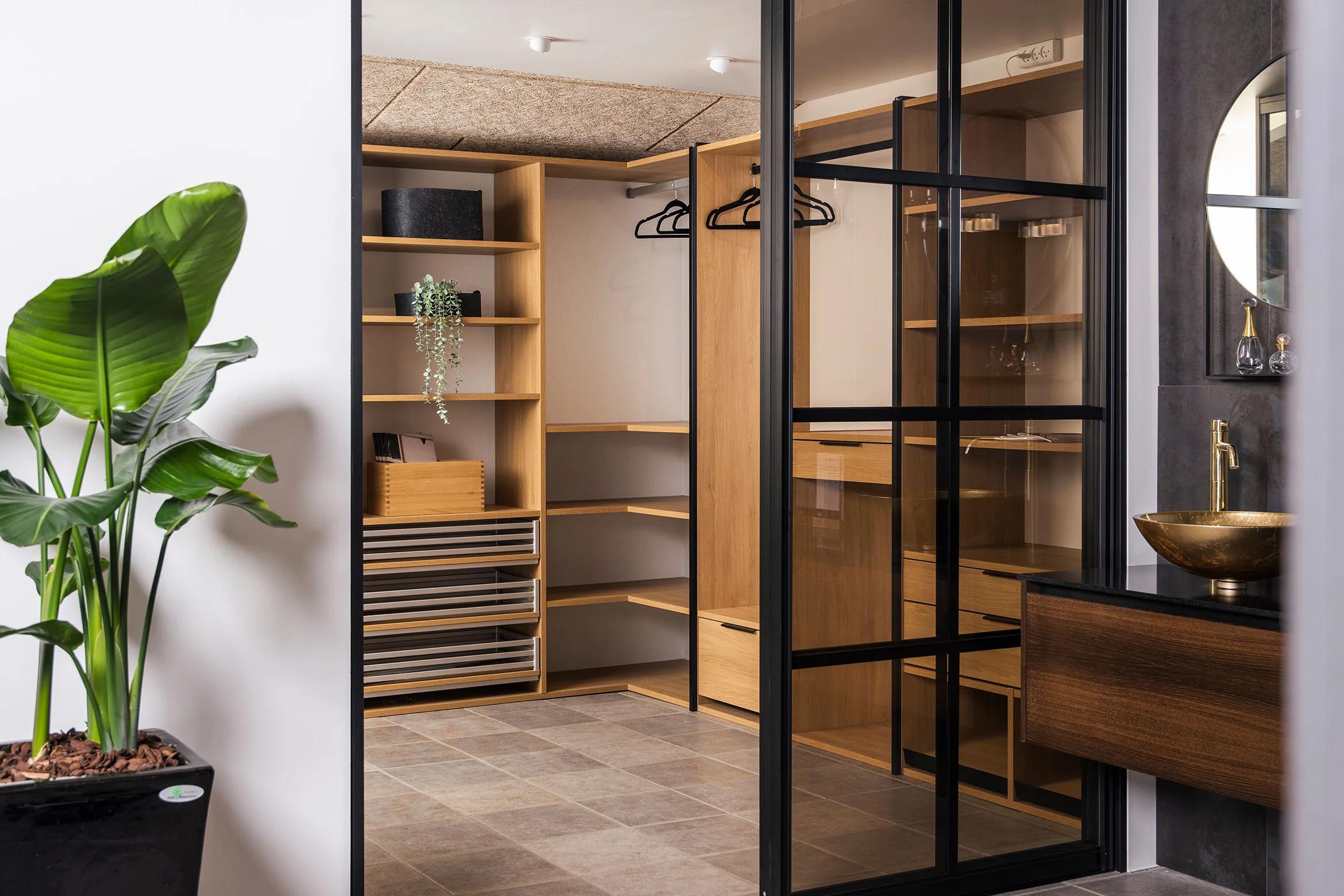 Walk-in-garderobe i eik bak glassdører med sorte sprosser