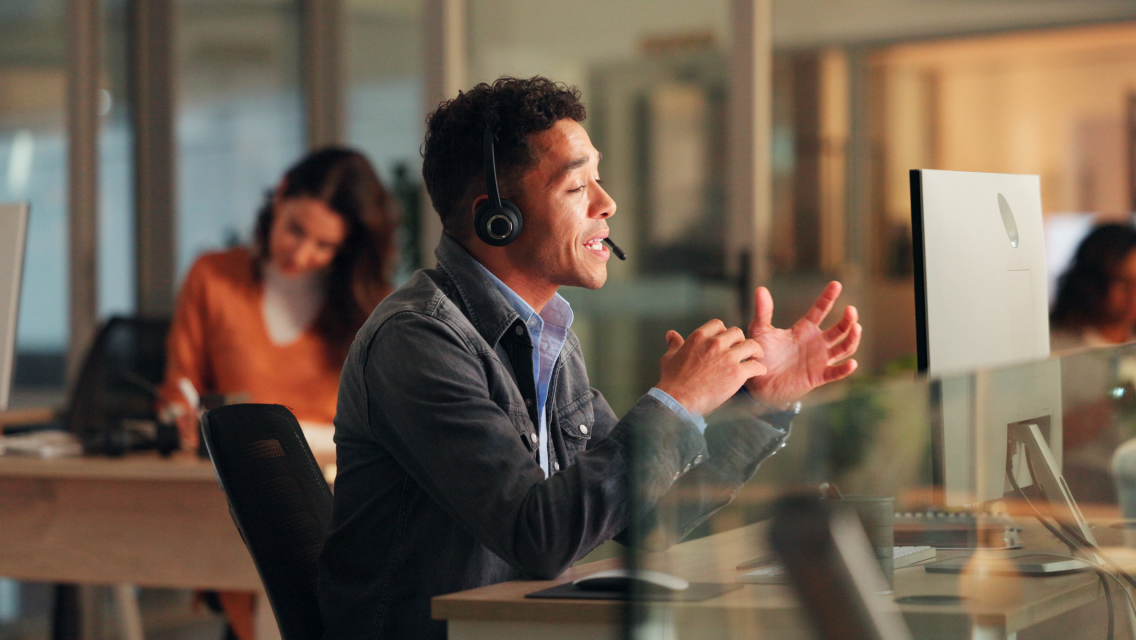 Real estate AI capabilities being utilized by man looking at computer screen while talking to a client on a headset