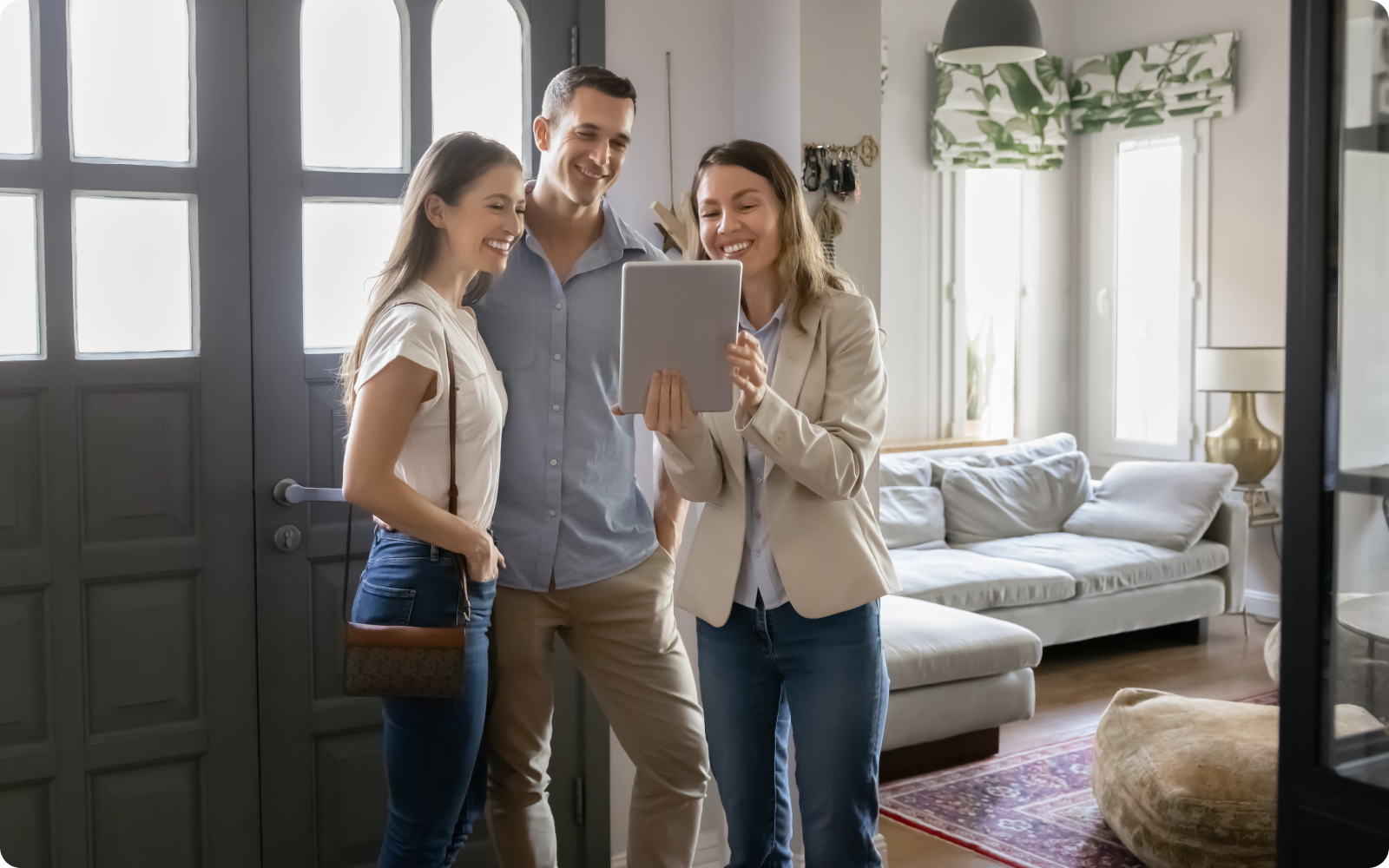 Agent with clients in a home looking at a tablet while reviewing the real estate agent website