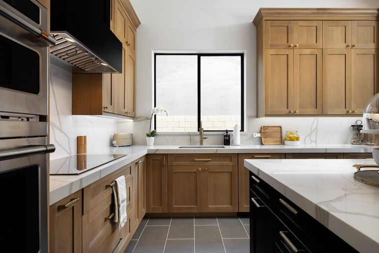 Kitchen with oak cabinets, veined marble counters and stainless double wall ovens